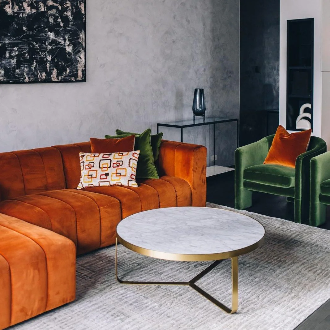 Living room with orange sofa, green chairs and marble coffee table