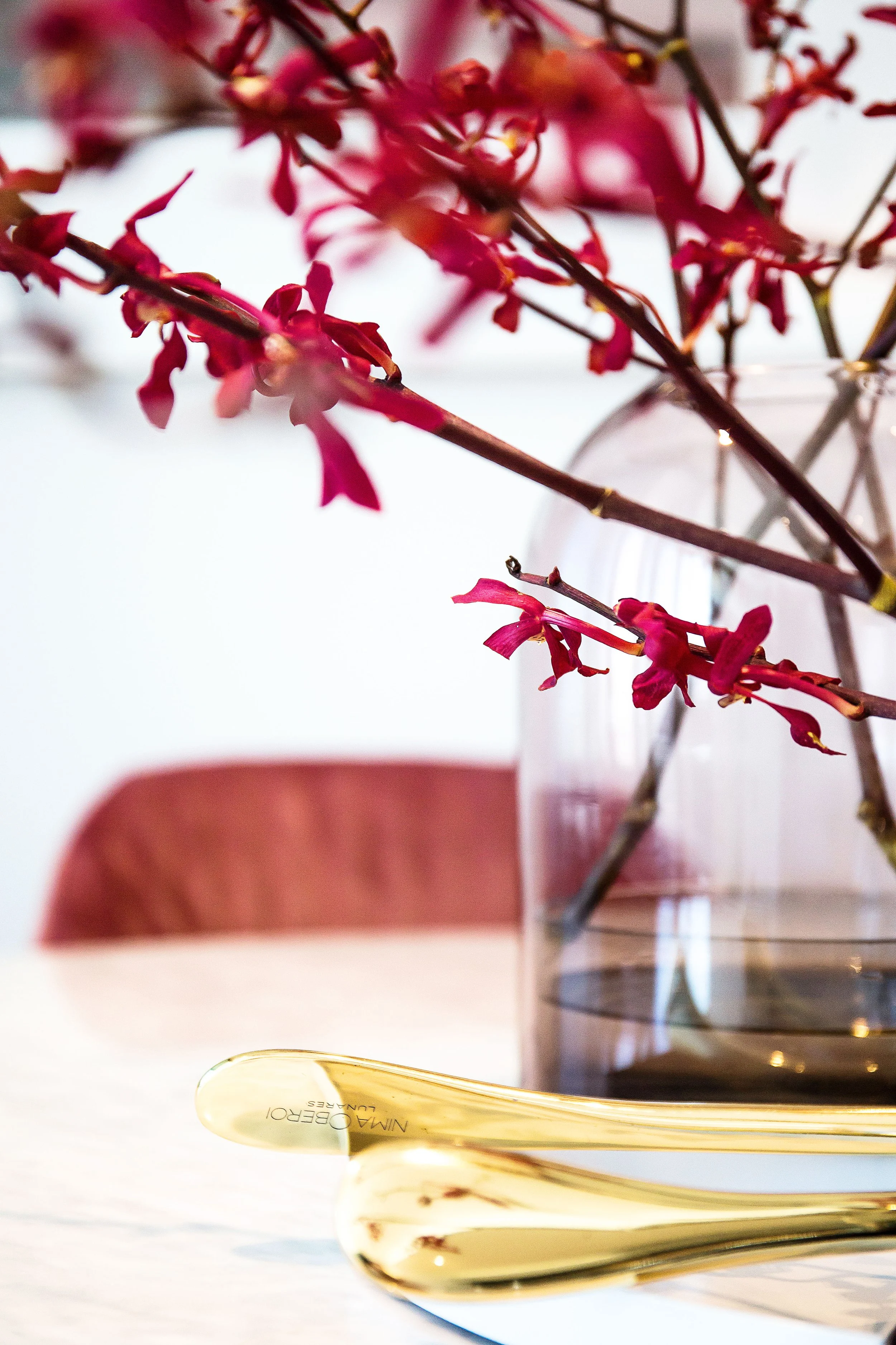 Apartment 1057 at Forge Docklands featuring a styled dining vignette with red florals in a glass vase and gold serving utensils, reflecting DMP Creative’s contemporary apartment interior design for Mirvac.