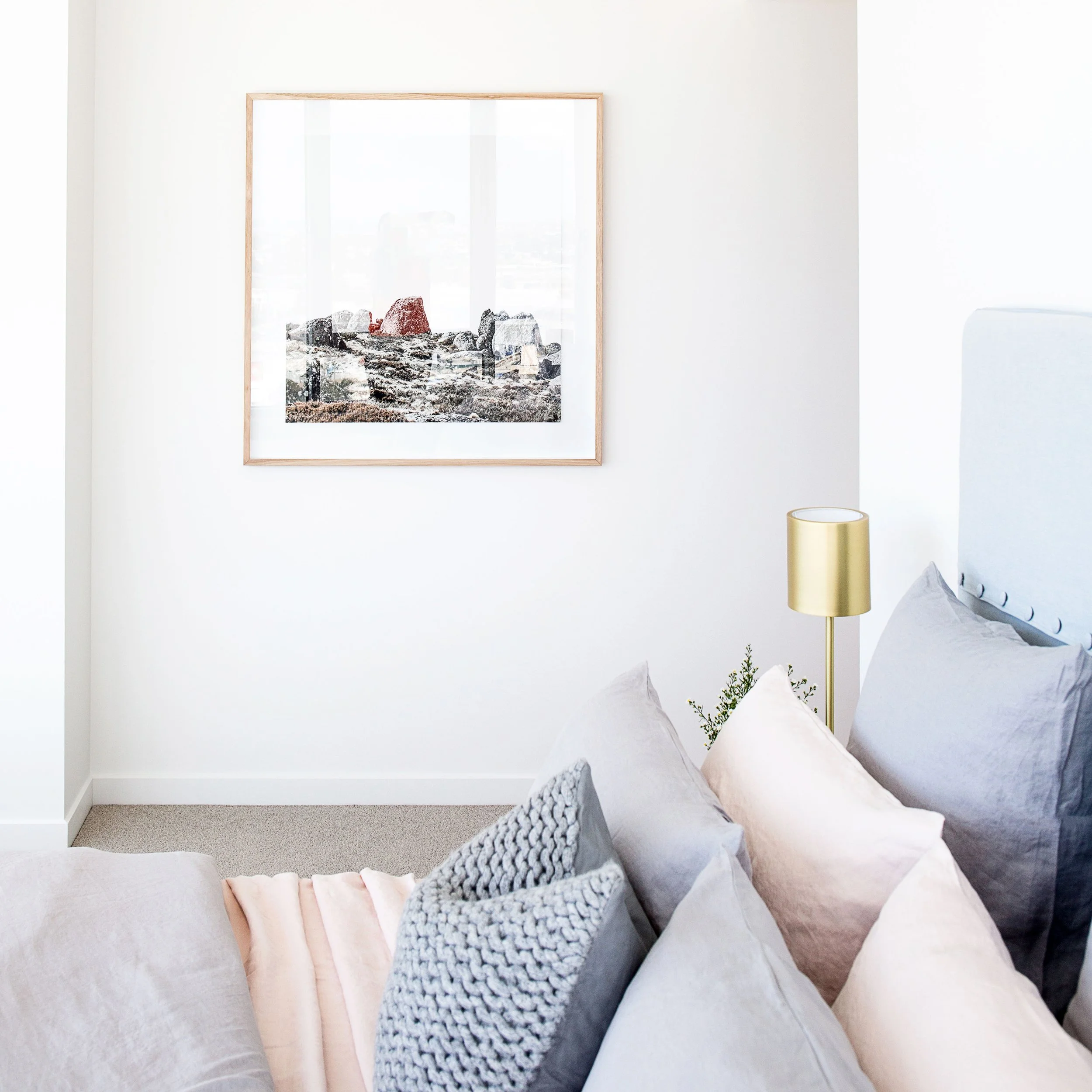 Master bedroom in Forge Docklands apartment featuring soft neutral bedding, upholstered bedhead and curated artwork by DMP Creative.