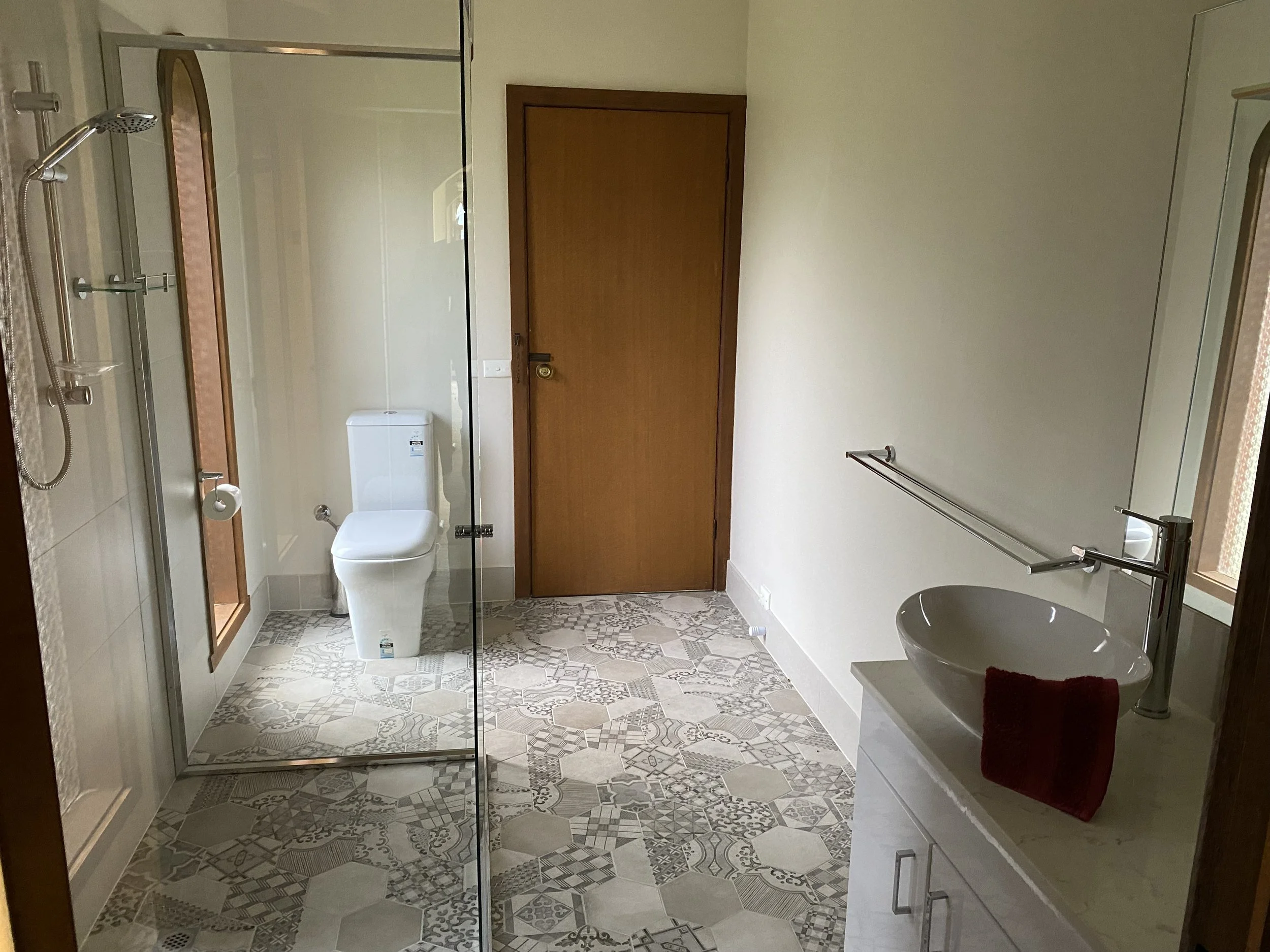 Dromana renovation before image of ensuite bathroom with glass shower, freestanding basin and mixed tile finishes