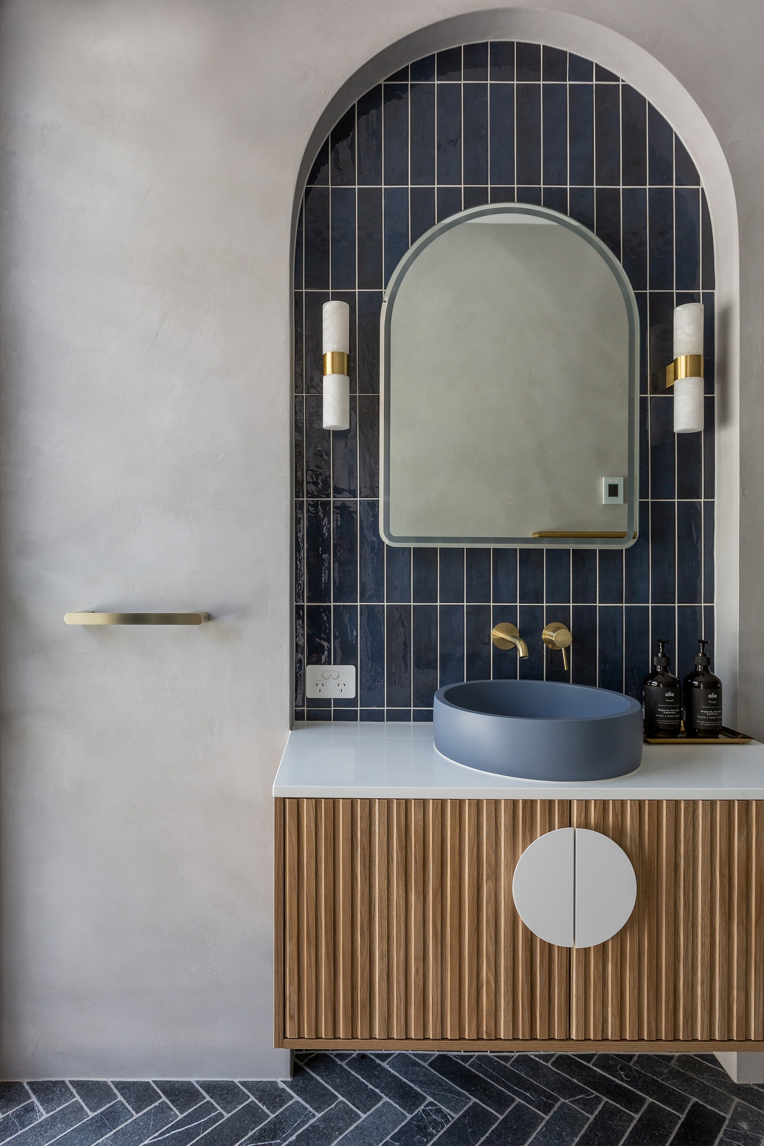 Bathroom vanity at Dromana residence with blue tiled arch, arched mirror, blue basin and fluted timber vanity