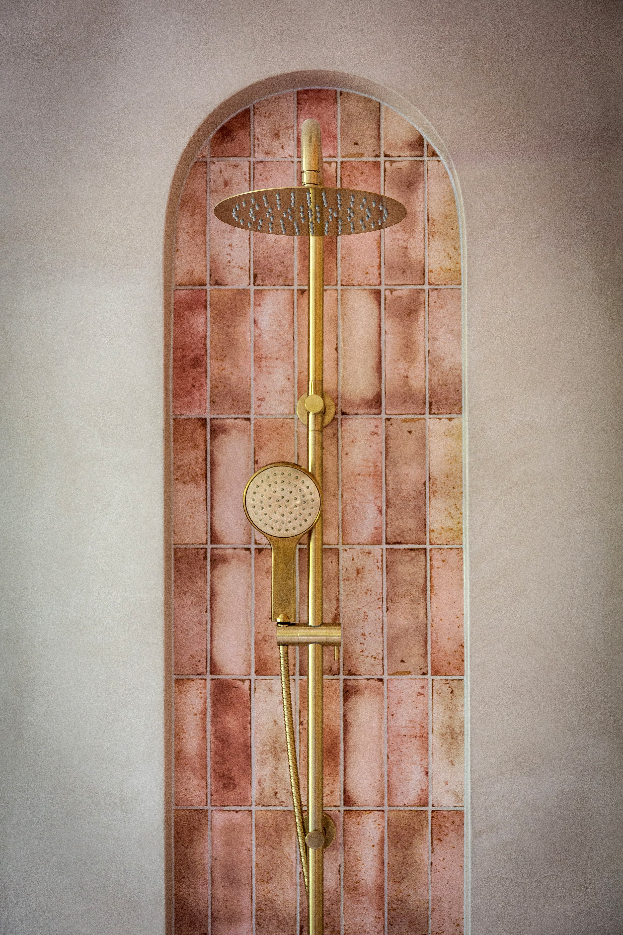 Bathroom at Dromana residence with pink tiled arches, brass shower, fluted timber vanity and blush basin
