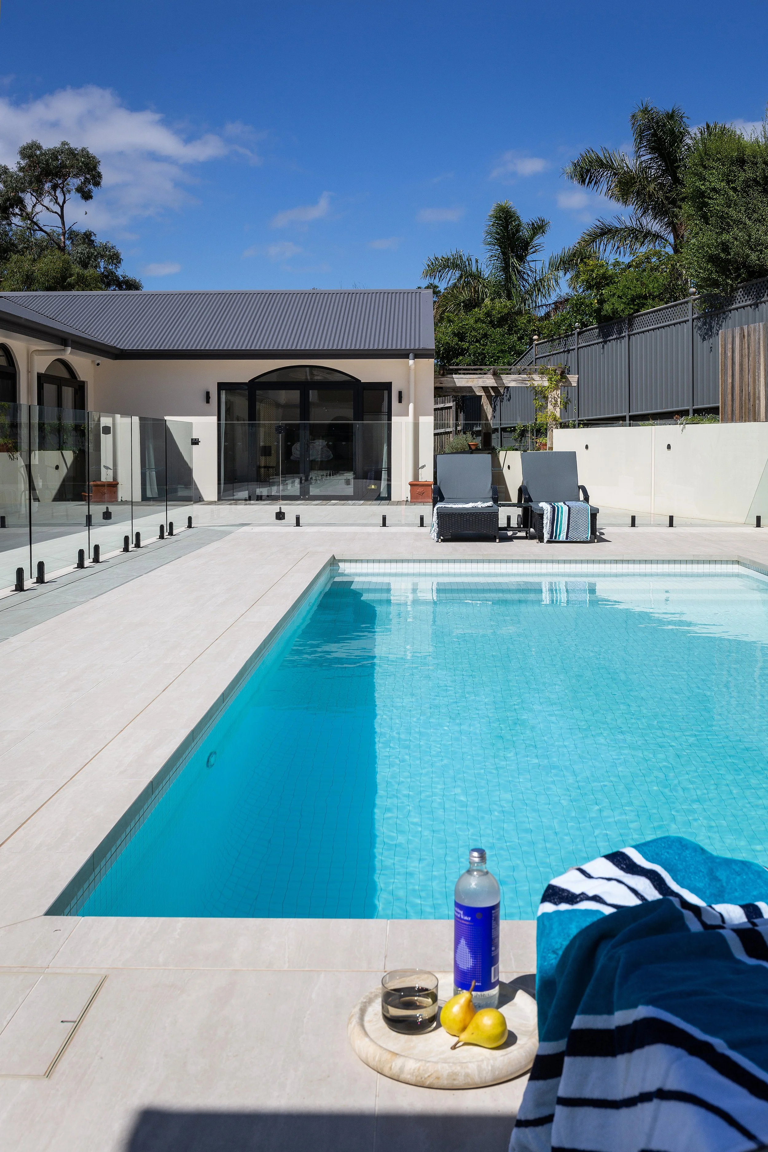 Swimming pool and modern exterior at Dromana residence with glass fencing and outdoor lounge chairs