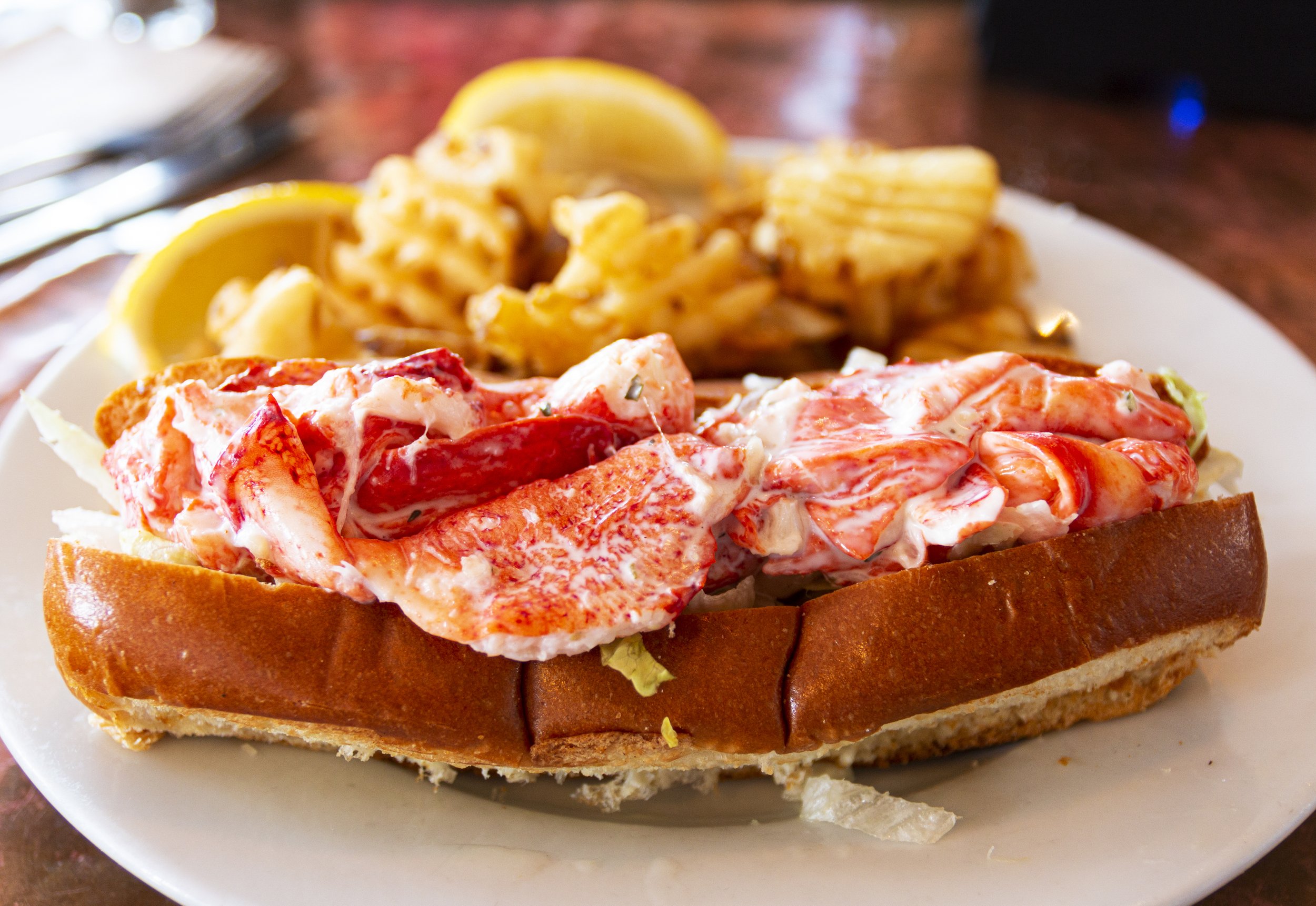 A fresh lobster roll served with waffle fries;