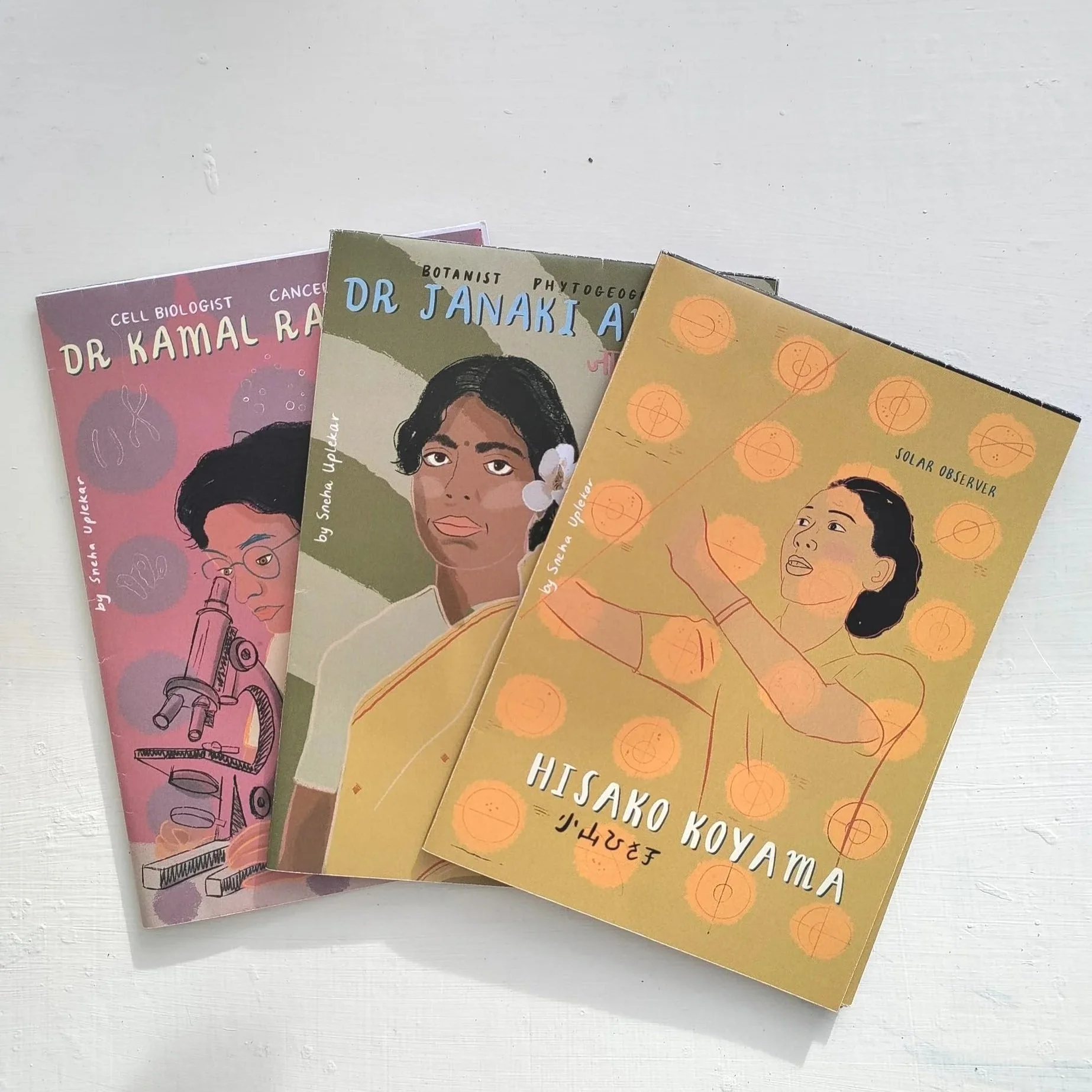 Three illustrated books about women scientists, featuring covers with portraits and scientific themes, placed on a white surface.