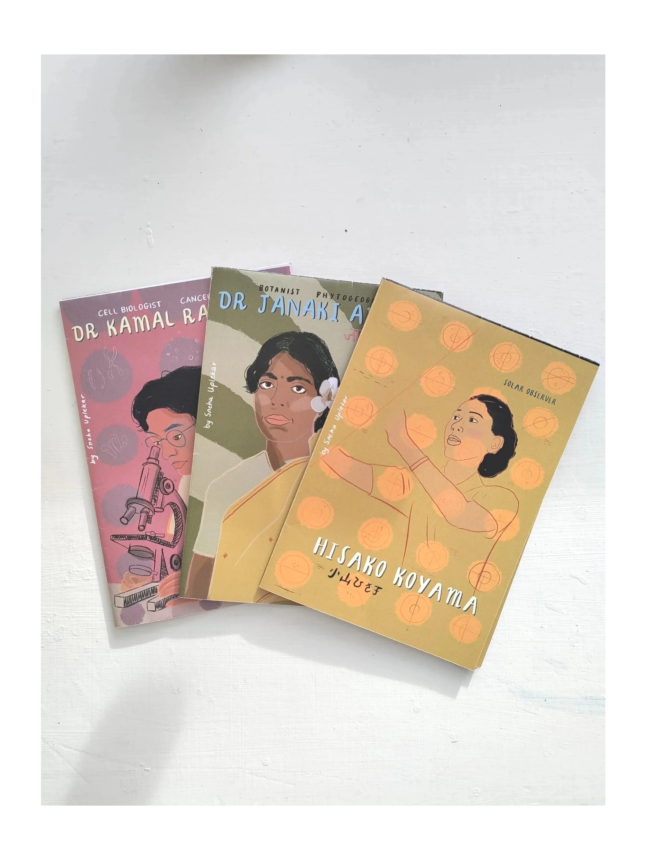 Three illustrated books about women scientists and astronomers are placed on a white surface, featuring titles and illustrations of the figures.