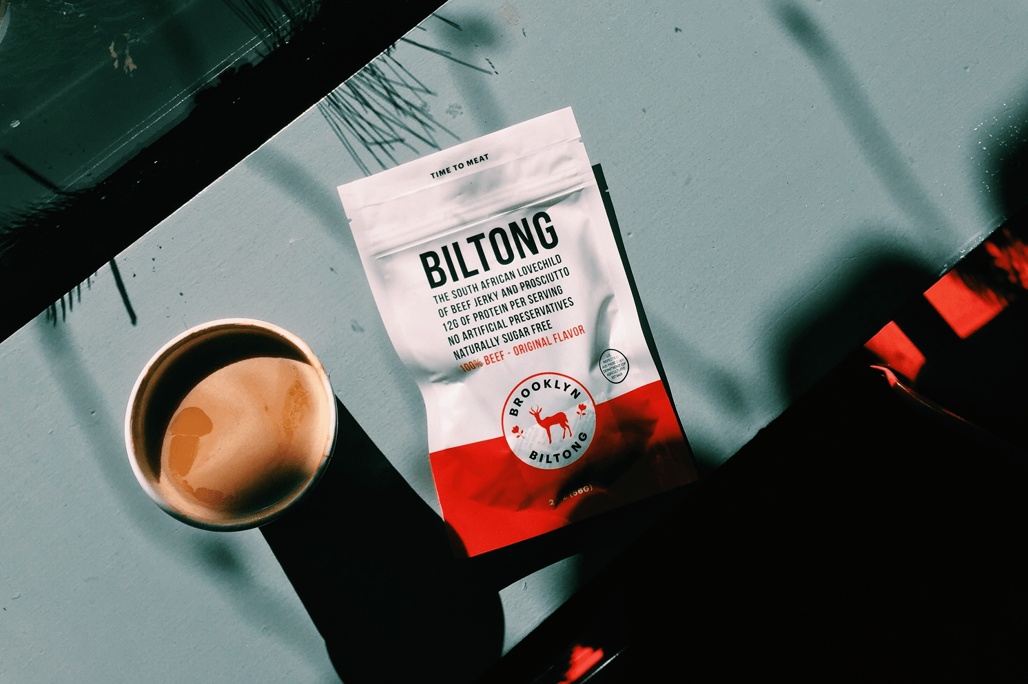 Brooklyn Biltong packaging in red, yellow, and navy blue for Original, Peri Peri, and Steakhouse flavors, styled with spices and ingredients.