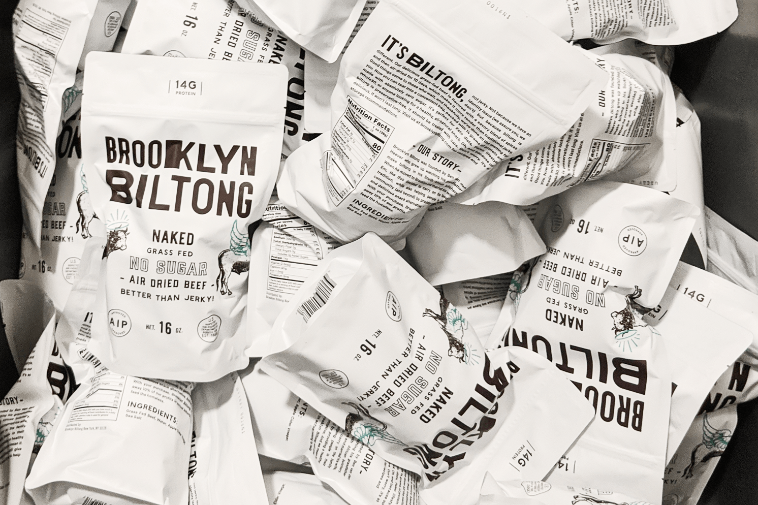 Collection of white Brooklyn Biltong Naked flavor pouches featuring black typography, illustrated antelopes, and minimal ingredient-focused packaging.
