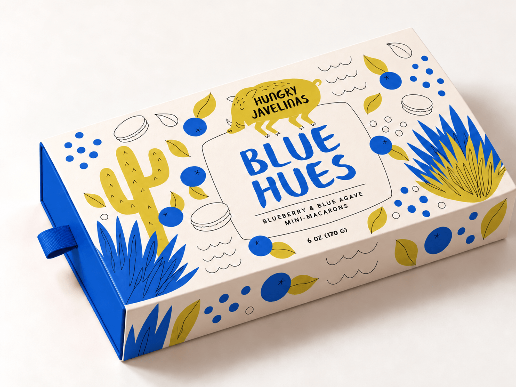 Hungry Javelinas Blue Hues mini-macaron packaging featuring bold blue lettering, illustrated blueberries, agave plants, yellow cacti, and a playful javelina logo.