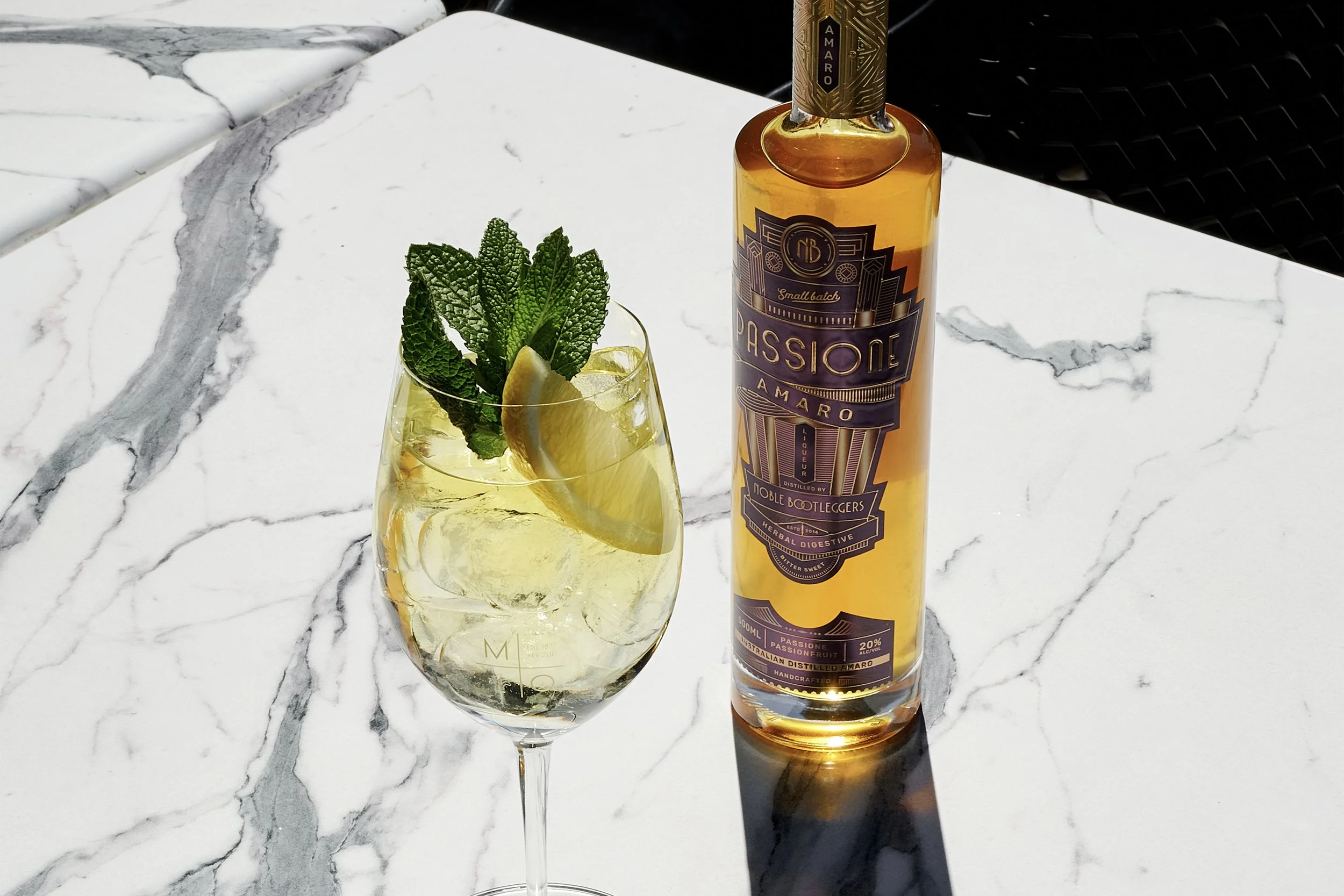 Noble Bootleggers Passione Amaro Spritz cocktail sitting on a marble table