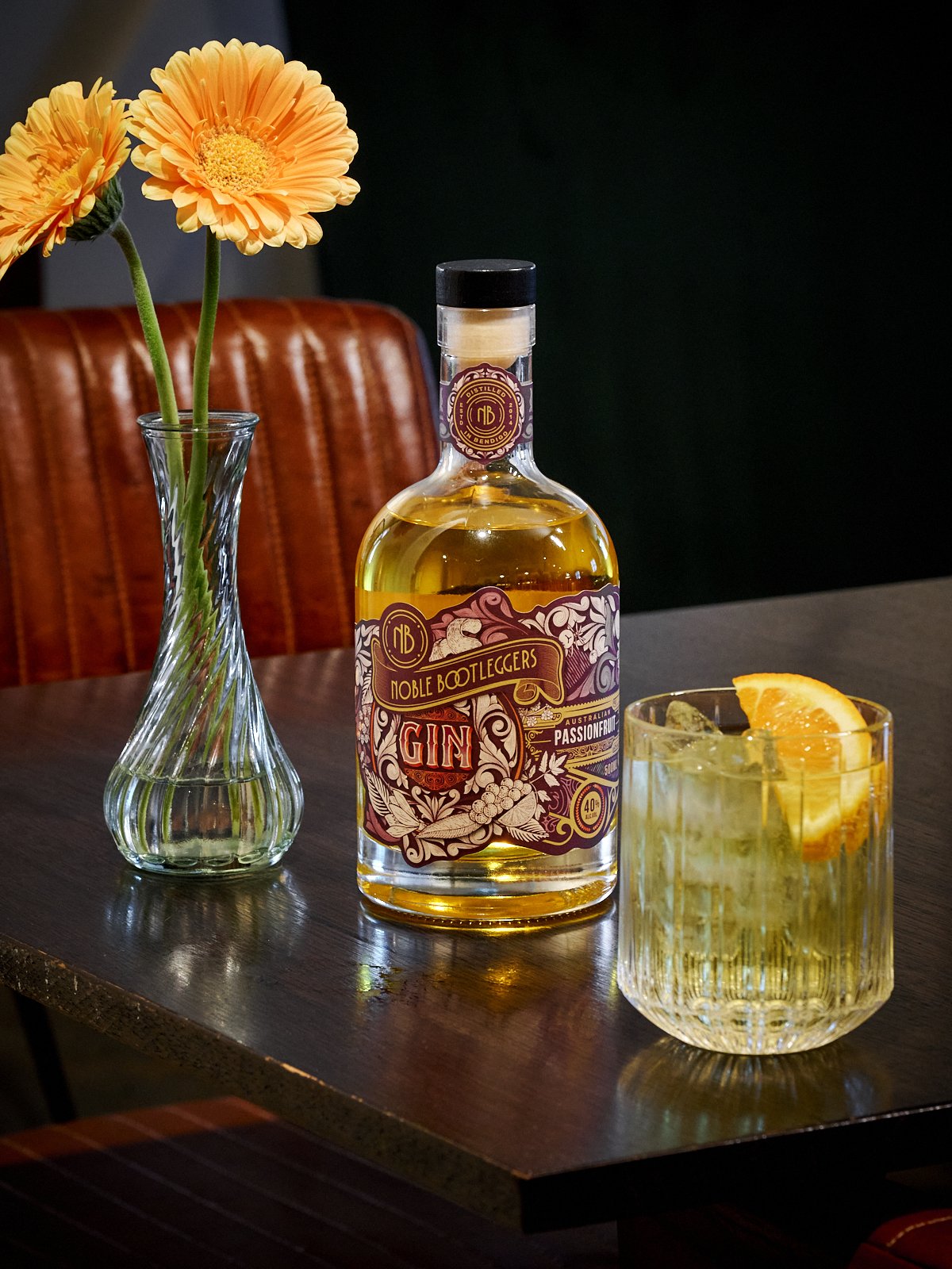 Noble Bootleggers Passionfruit gin, accompanied with a Passionfruit gin & tonic, garnished with a slice of lemon.