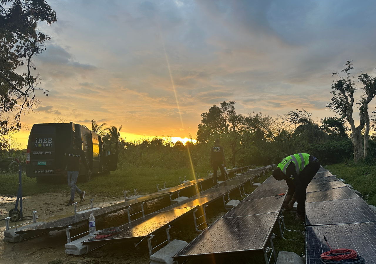 Three employees from Iree Solar setup a solar microgrid panel in rural Jamaica.