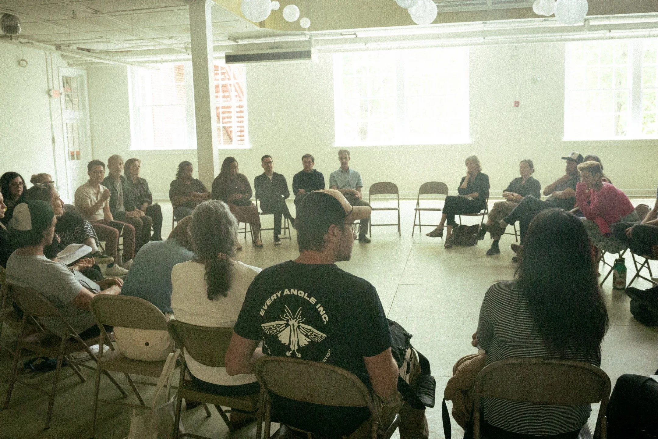 A group of participants sat in a circle, gathers to discuss community resilience.
