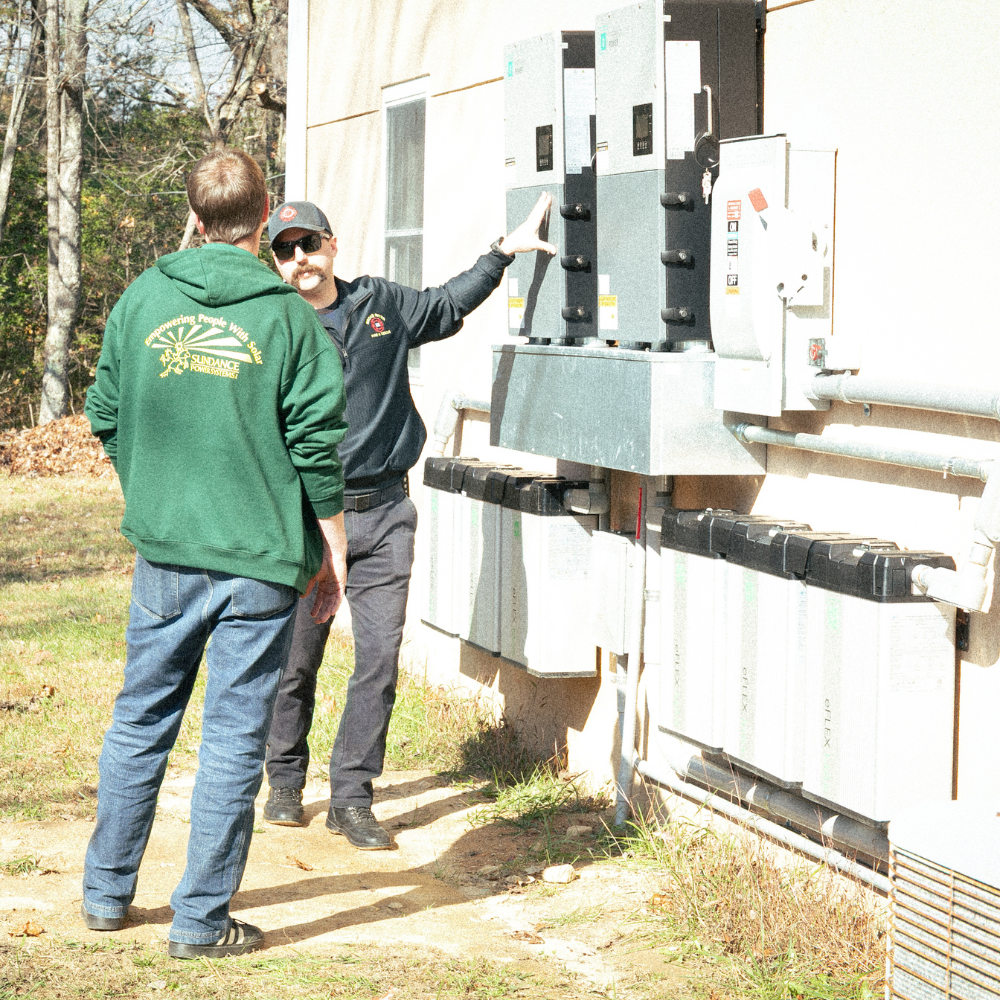 A volunteer fire officer from Broad River Fire Department shows a Footprint Project employee a electric panel.