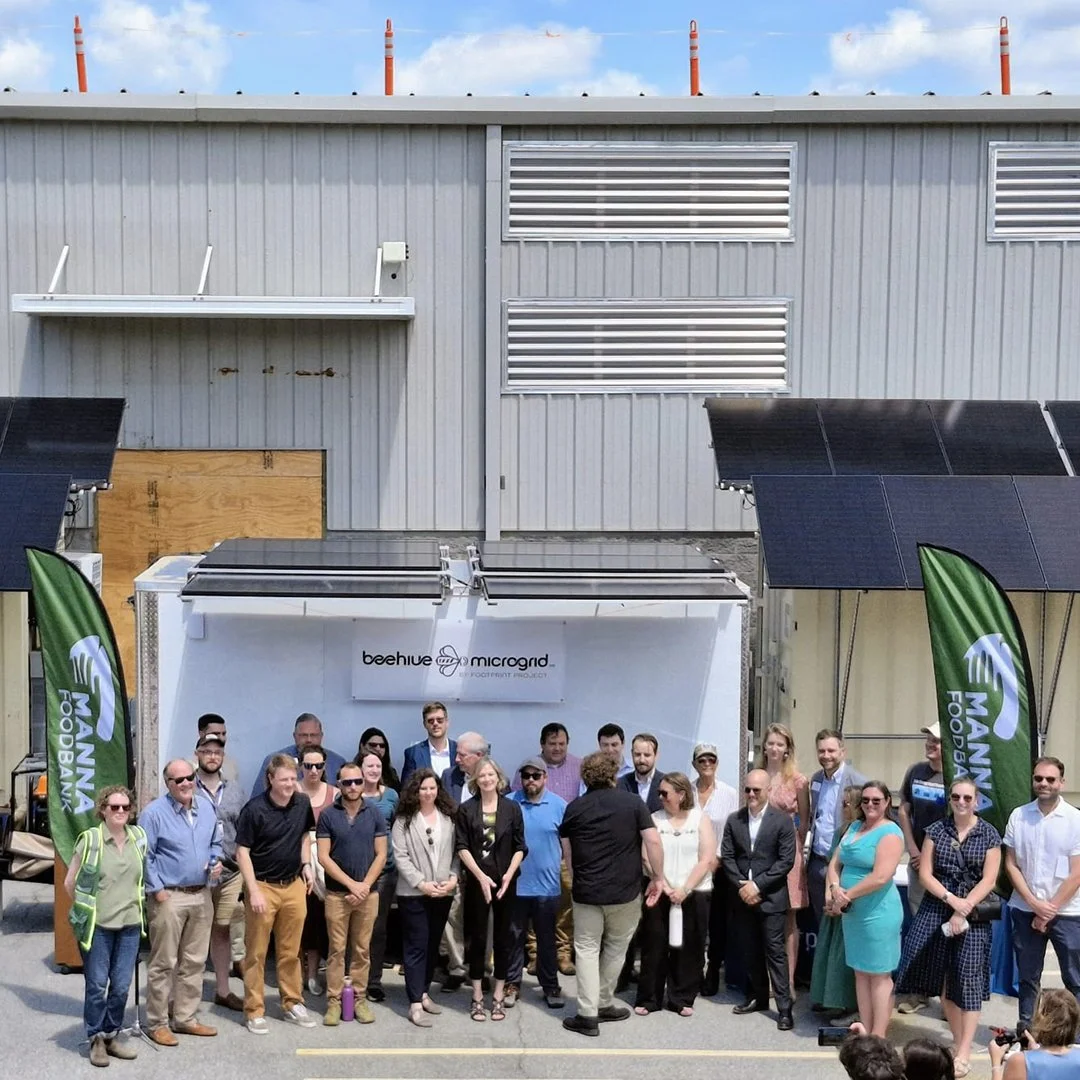 Image of a group of people standing in front of a trailer at the launch of the Beehive Microgrid™