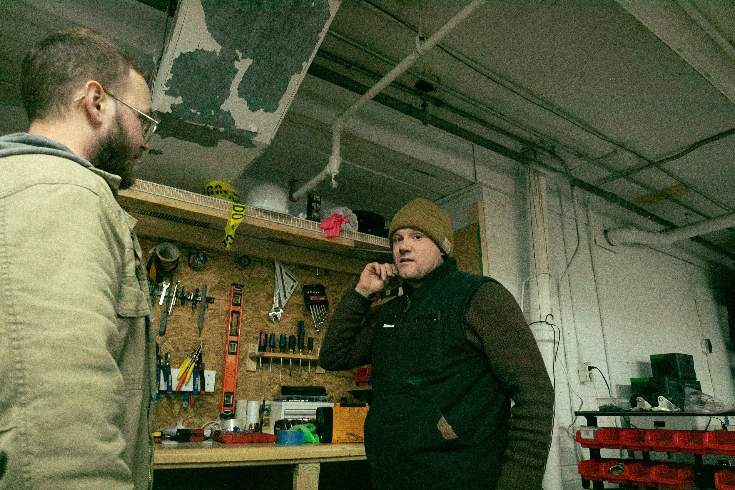 Two people talk in front of a work bench in a warehouse