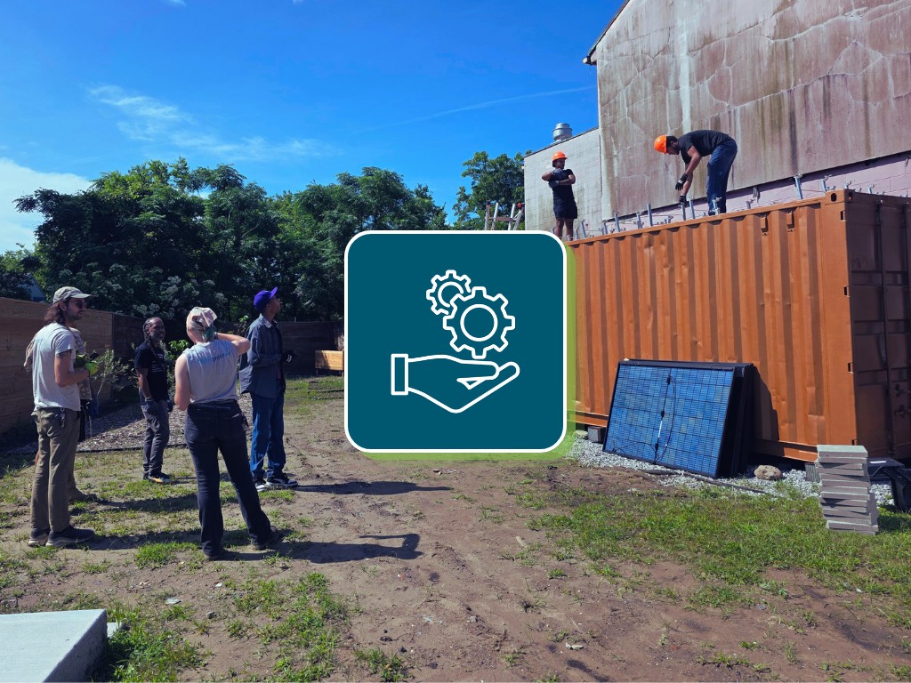 Photo of an outrach ebent with staff working on a shipping container. In the center of the image is an icon with gears and a hand - representing support.