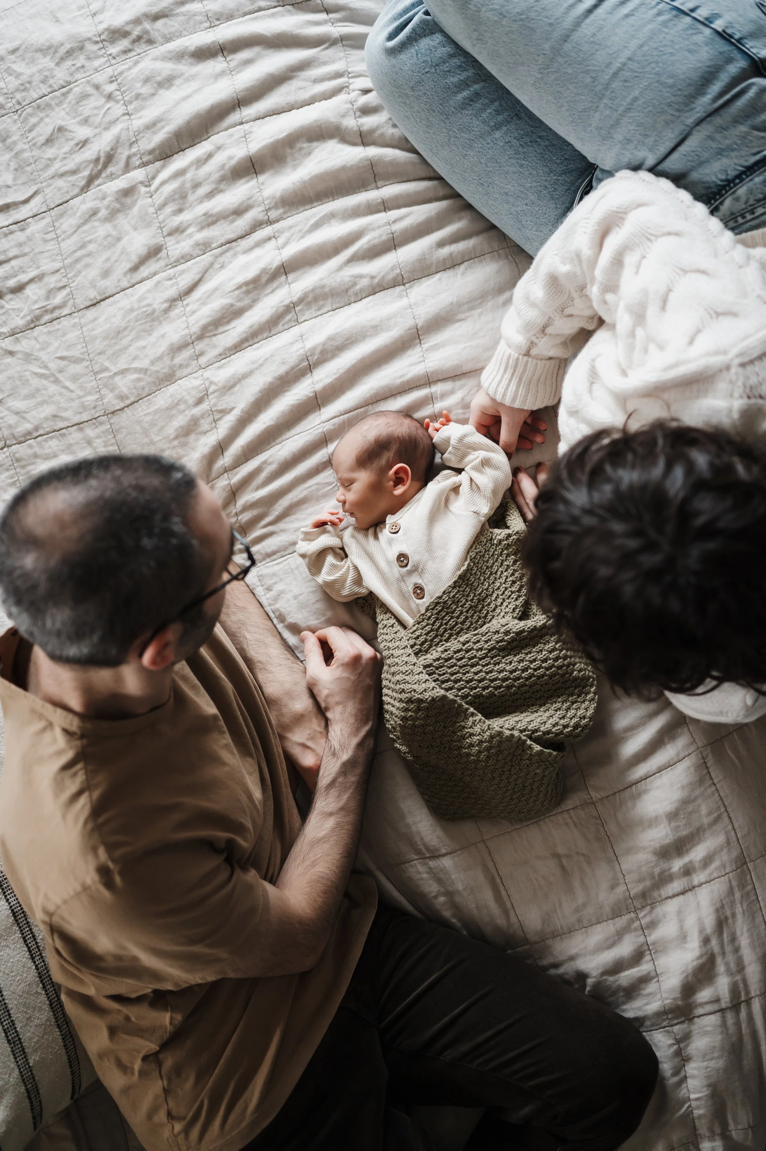Parents on bed with baby during lifestyle photo session
