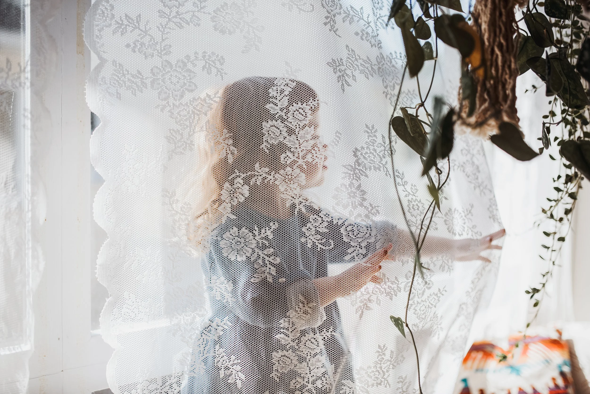 Girl peeking through sheer curtain