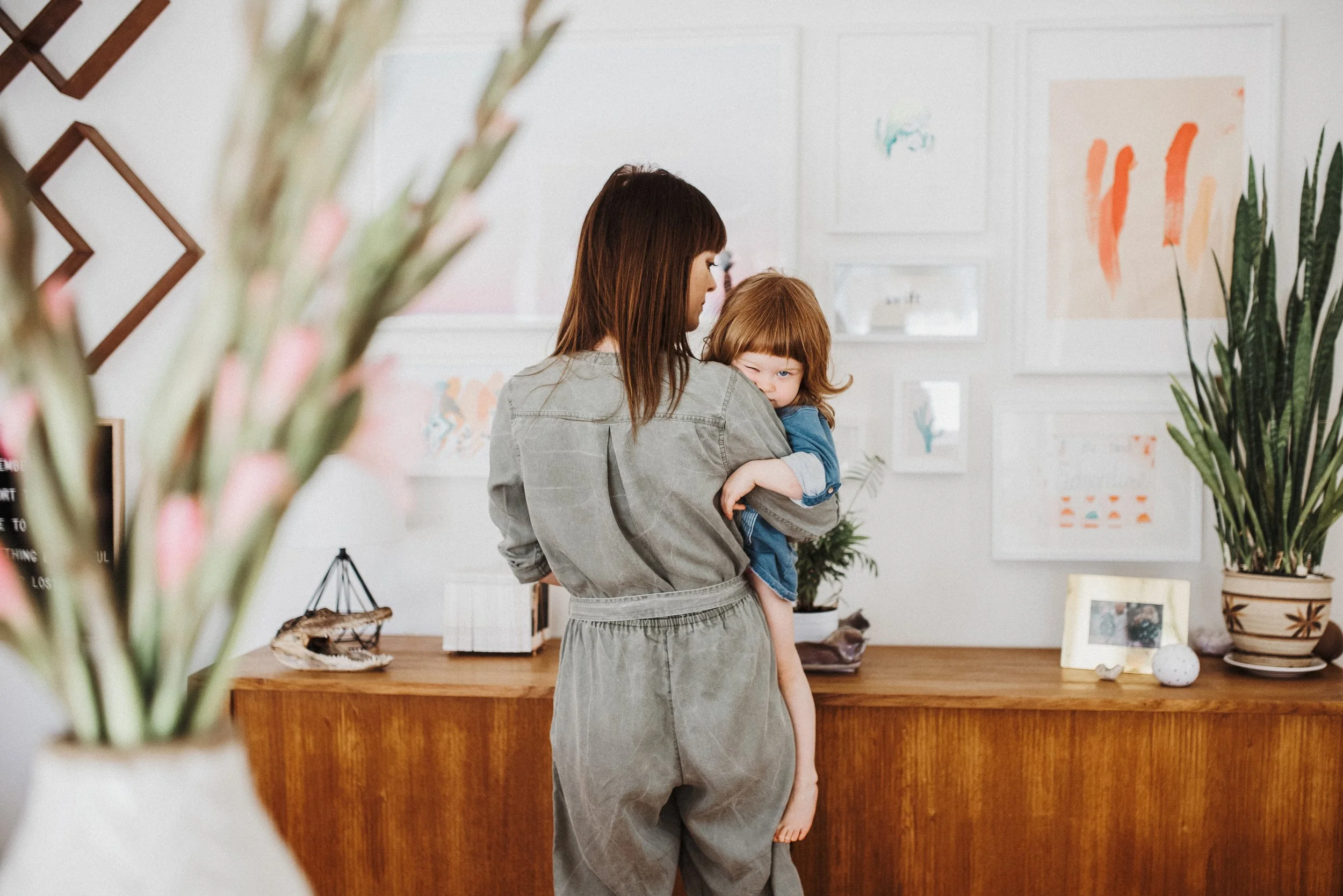 Mom holds young daughter on hip during in home lifestyle photography session
