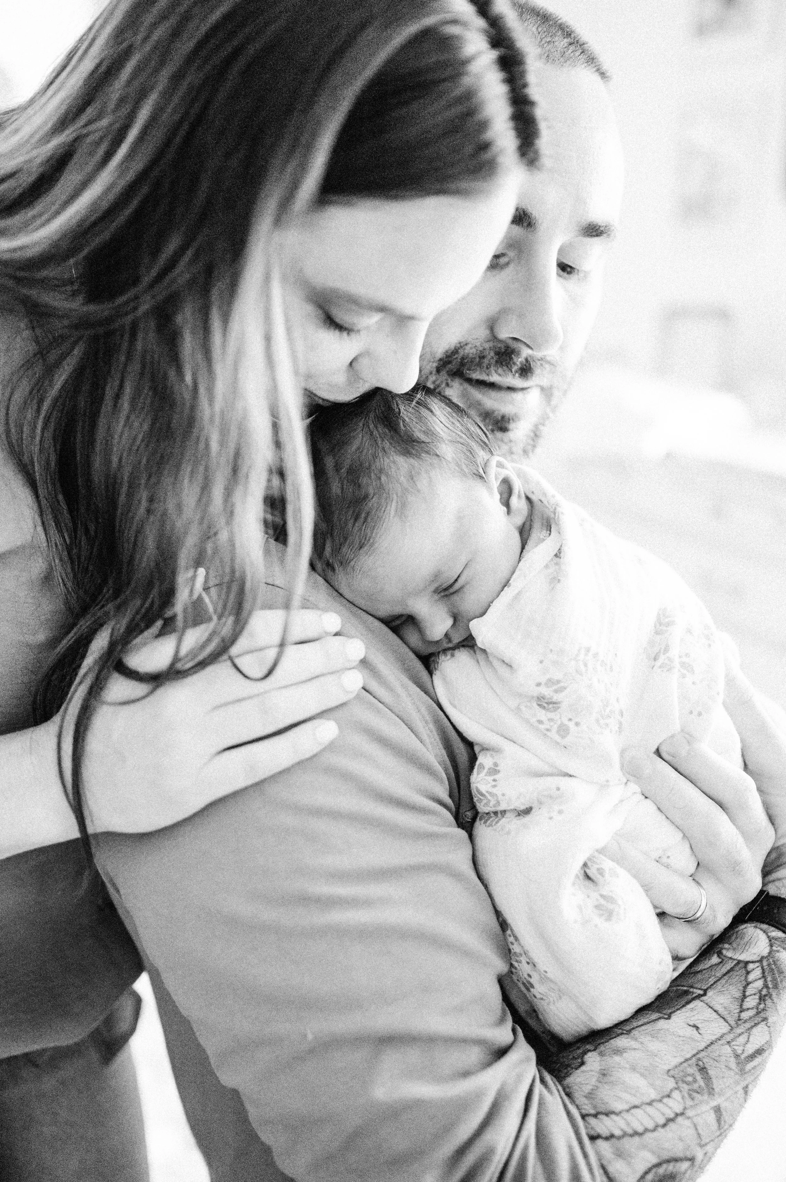 Parents snuggle with newborn during lifestyle photo session