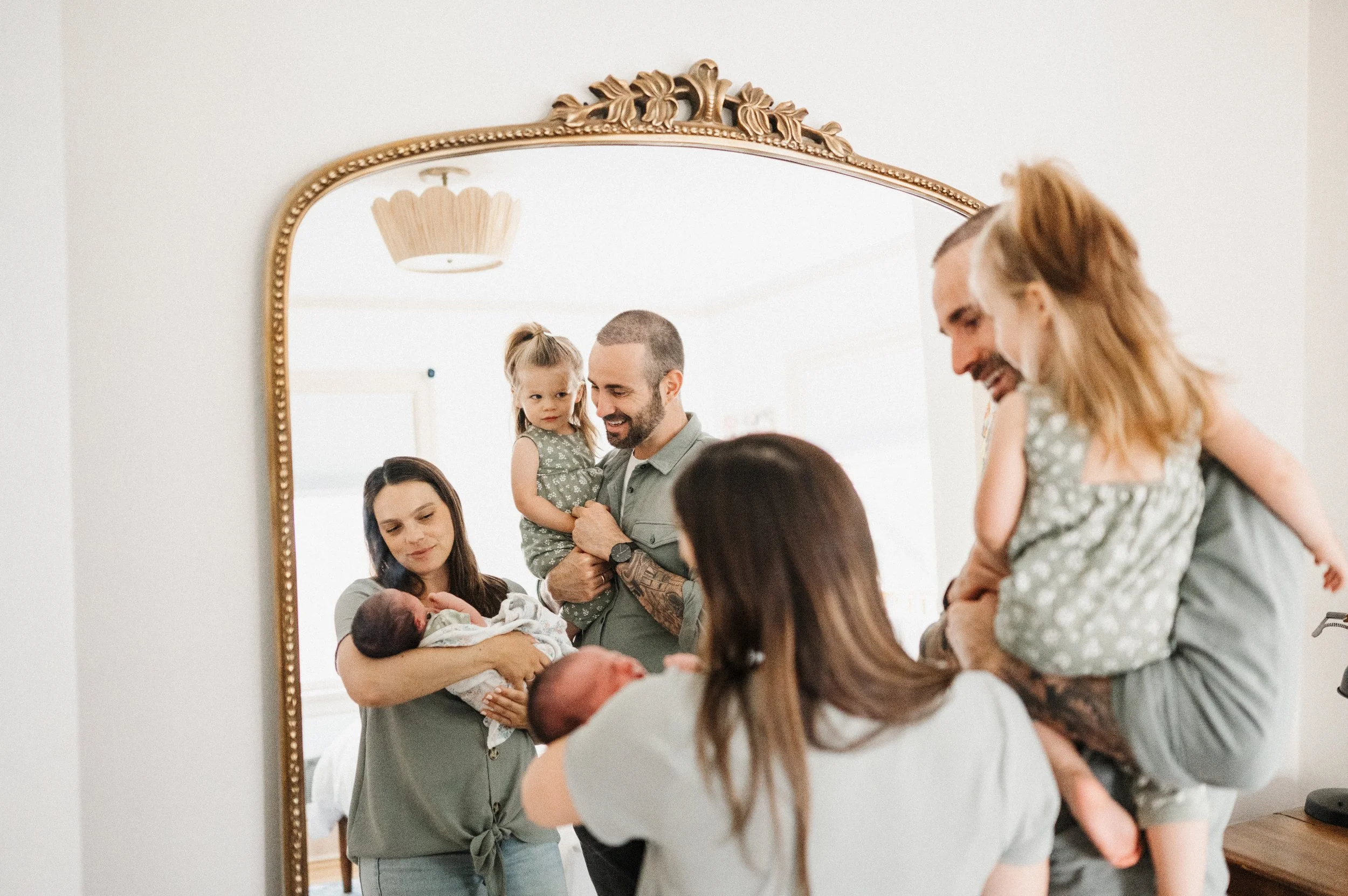 Family of four stand in front of mirror during newborn photo session
