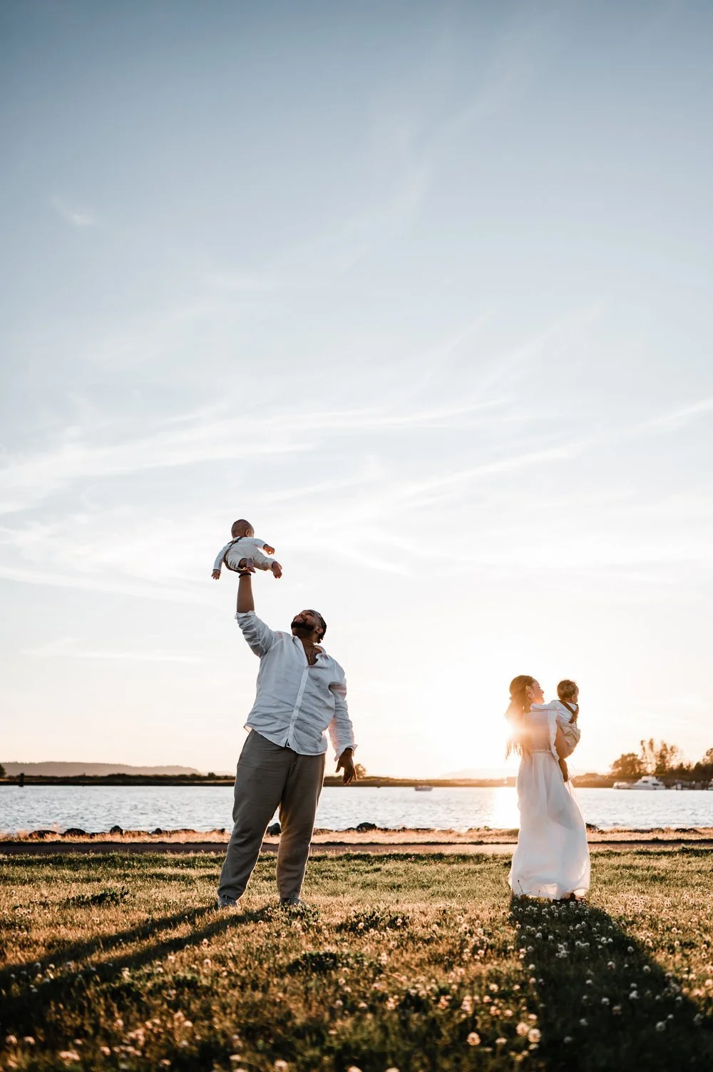 mom and dad playing with twin babies at sunset