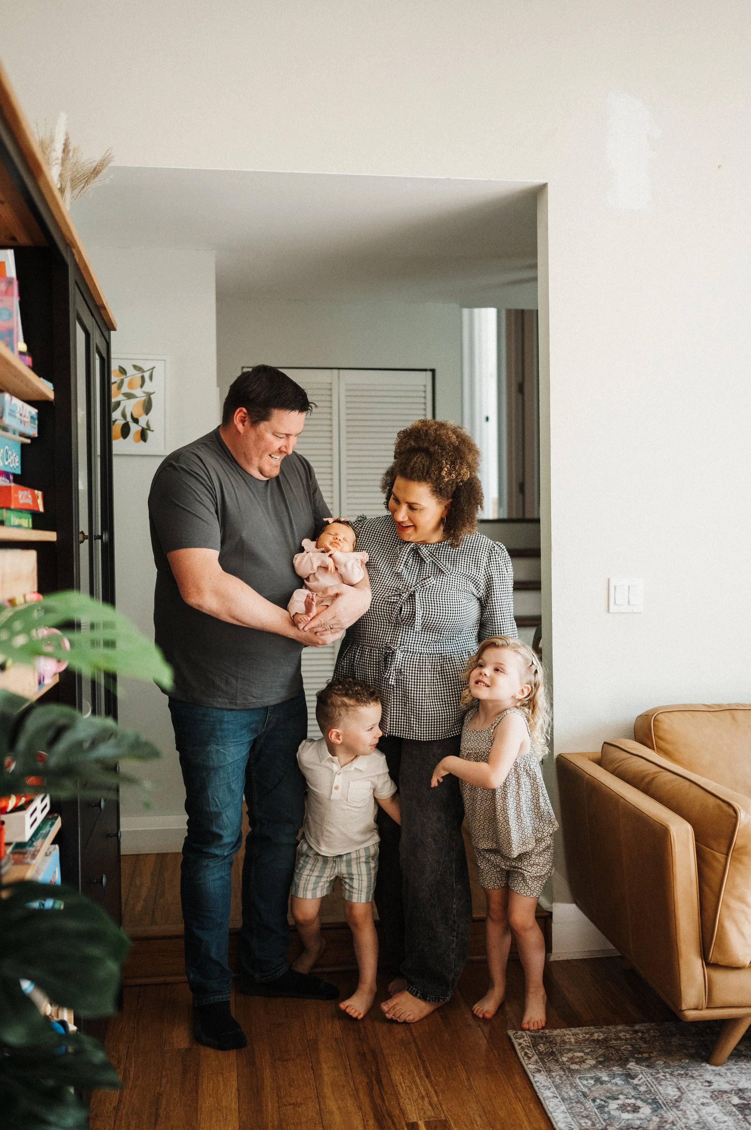 family of five with new baby standing together in doorway