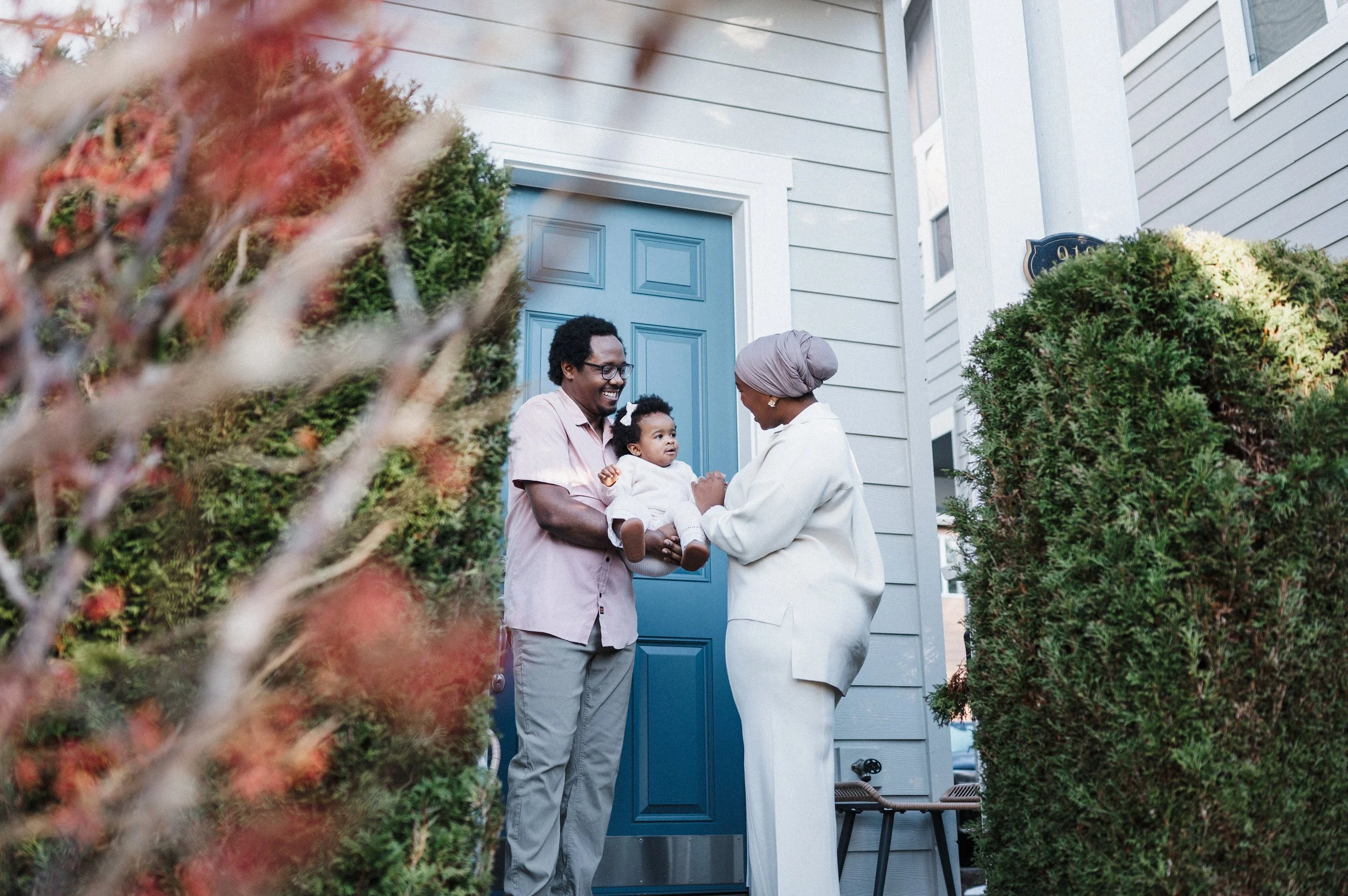 family of three standing outside their house