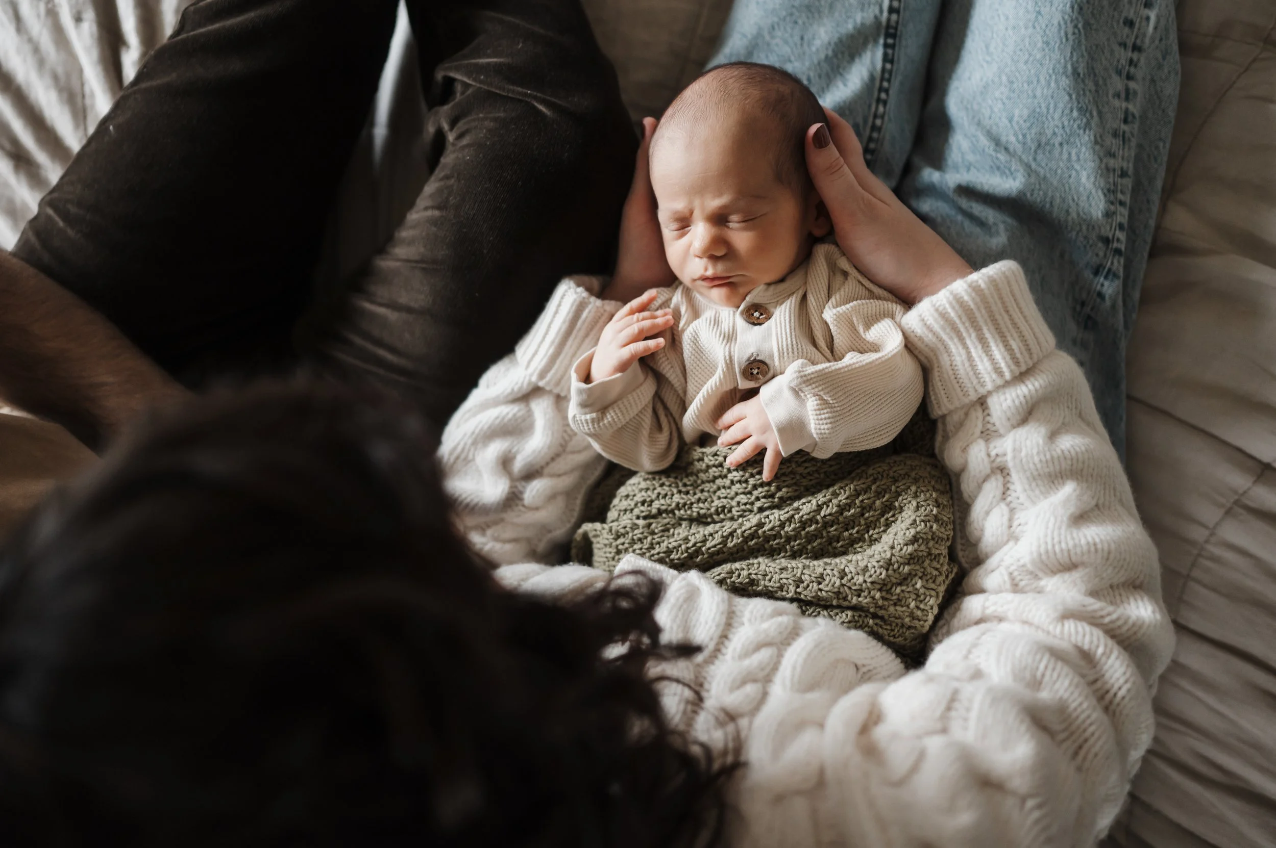 mom and dad holding newborn baby on bed