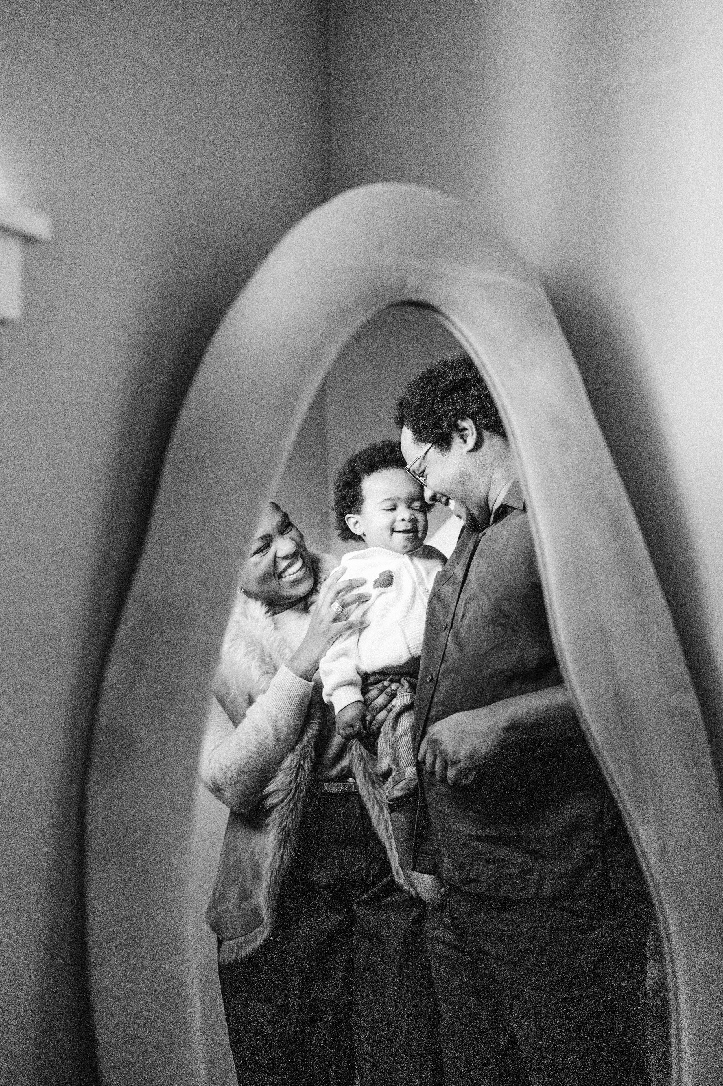 mom, dad and child standing together in front of mirror
