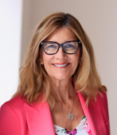 A headshot photograph of Flay Charbonneau wearing glasses and a pink blazer.