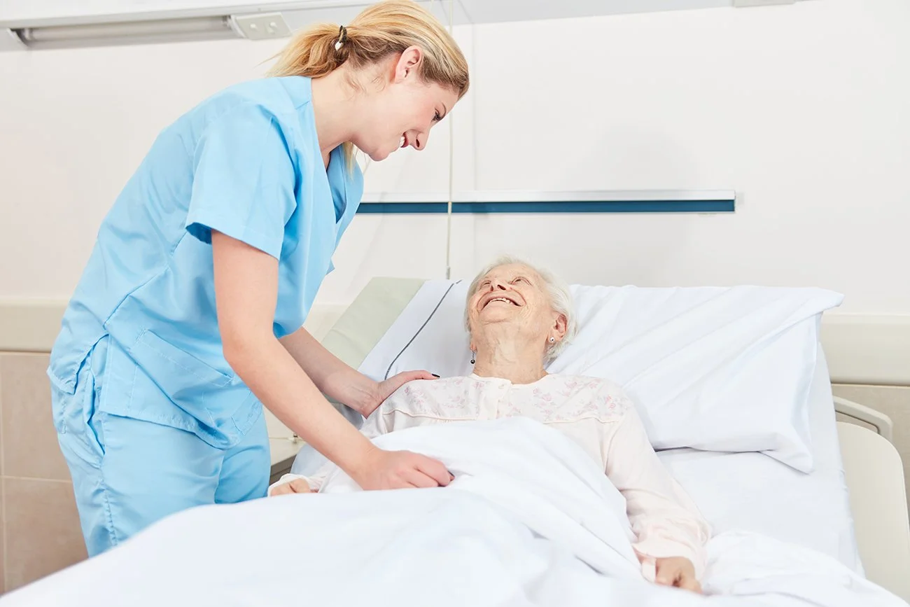 Nurse at bedside in a hospital with elderly woman