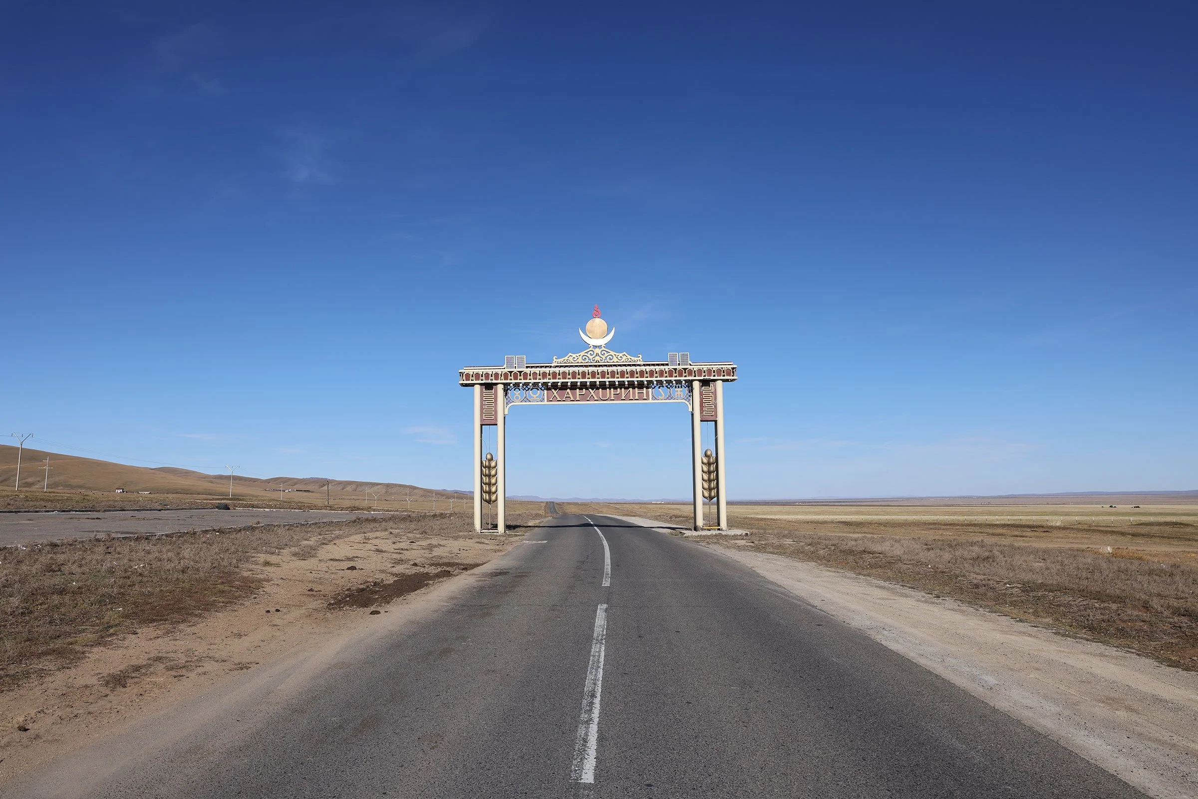 Rak landsväg på den mongoliska stäppen, med en port med texten Karakorum