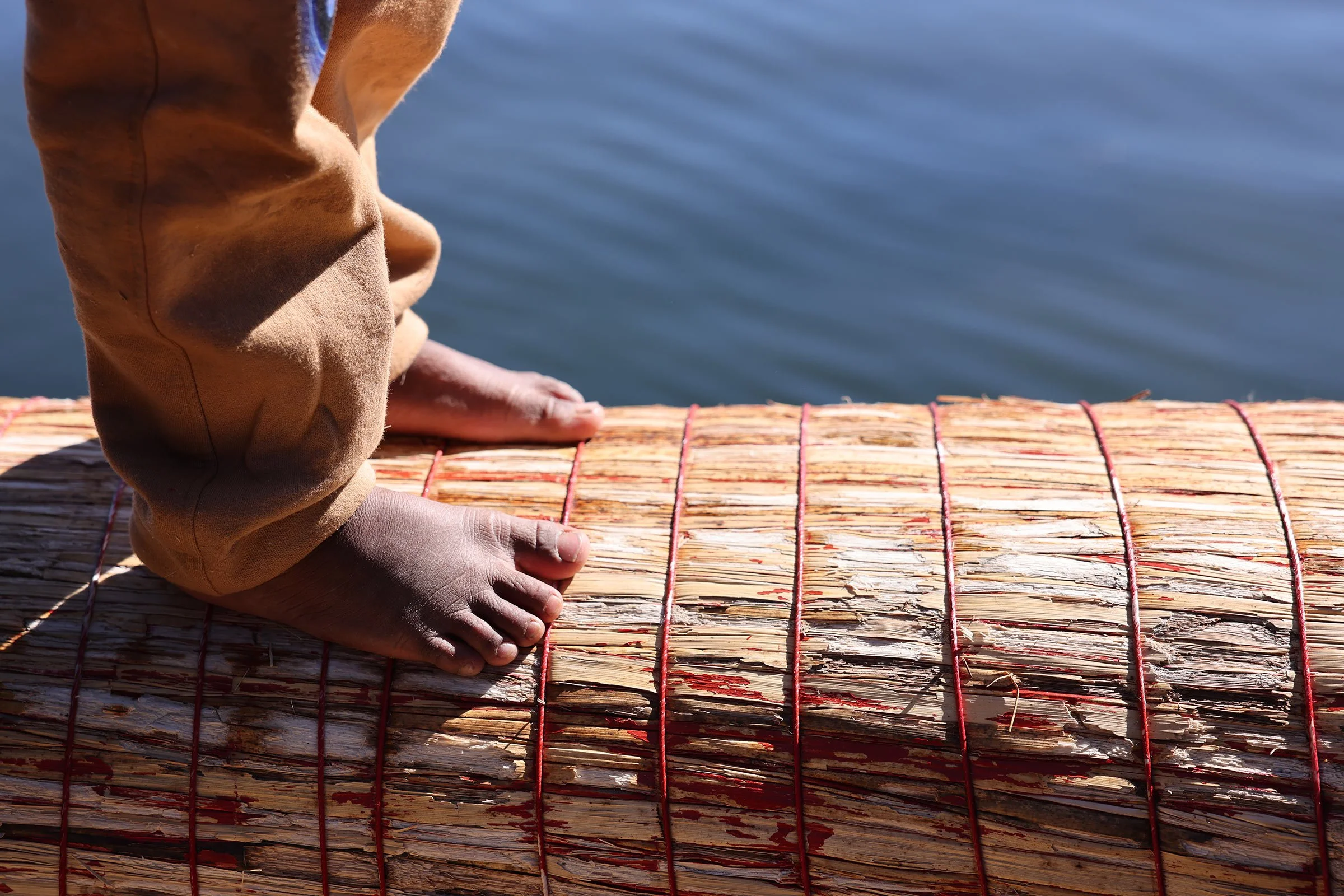 Barfota barnfötter på vasen på en totorabåt. På Uros flytande vassöar i Titicacasjön, Peru.
