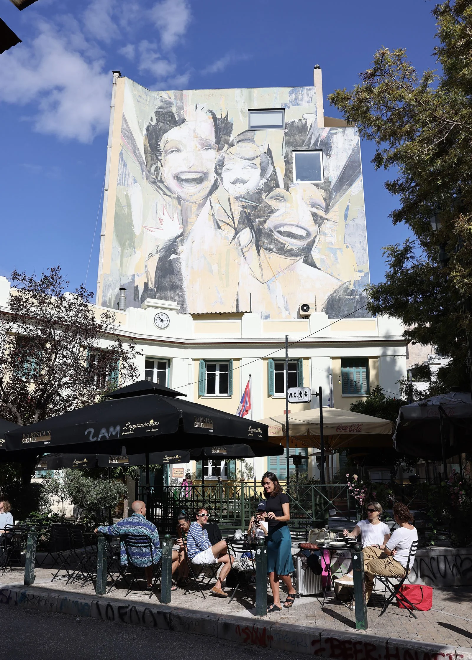 Streetart i form av tre skrattande ansikten på en husfasad – Untitled av Alexandros Vasmoulakis – i Aten, Grekland