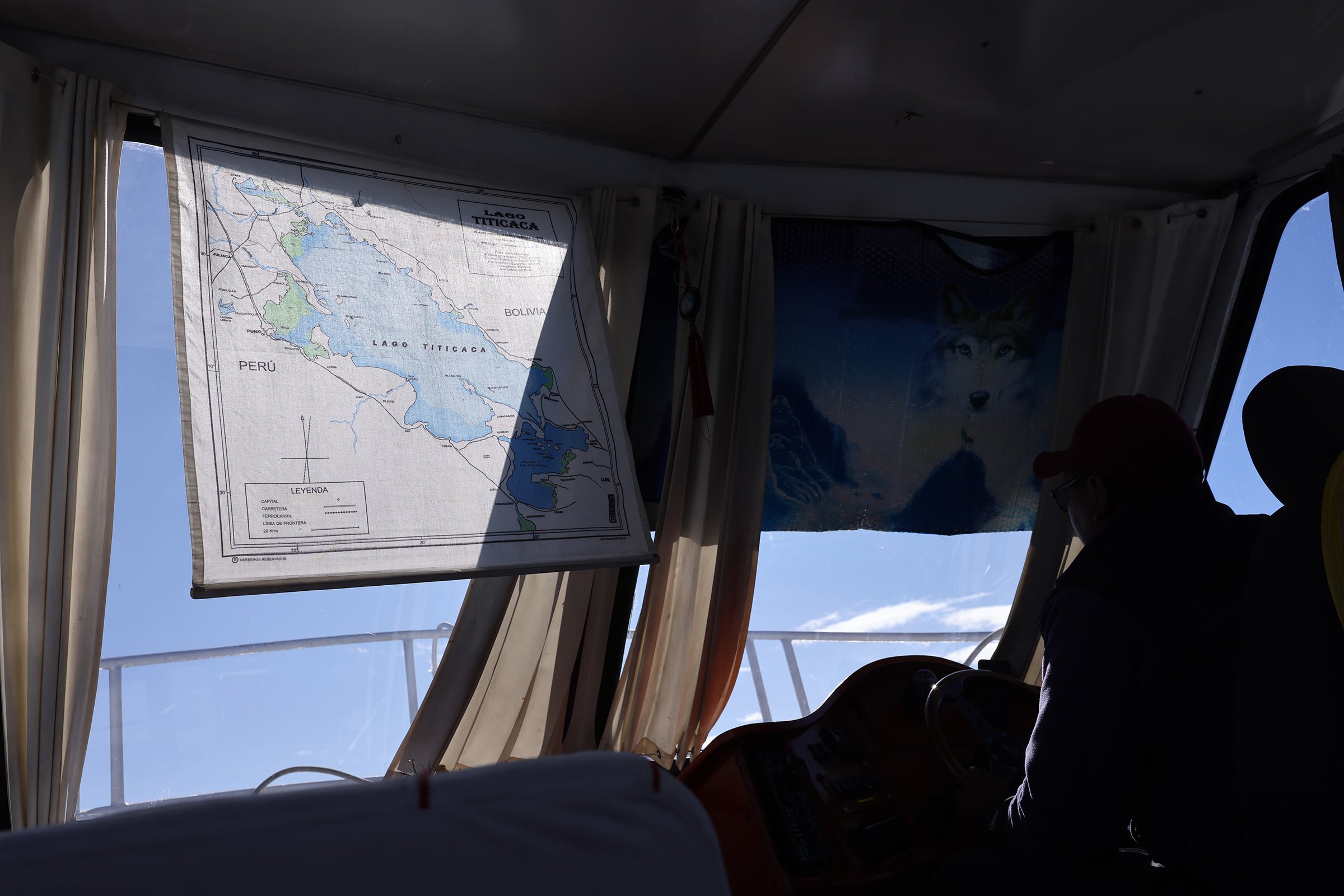 Inuti en båt på Titicacasjön, med en karta och en bild av en varg hängandes i fören