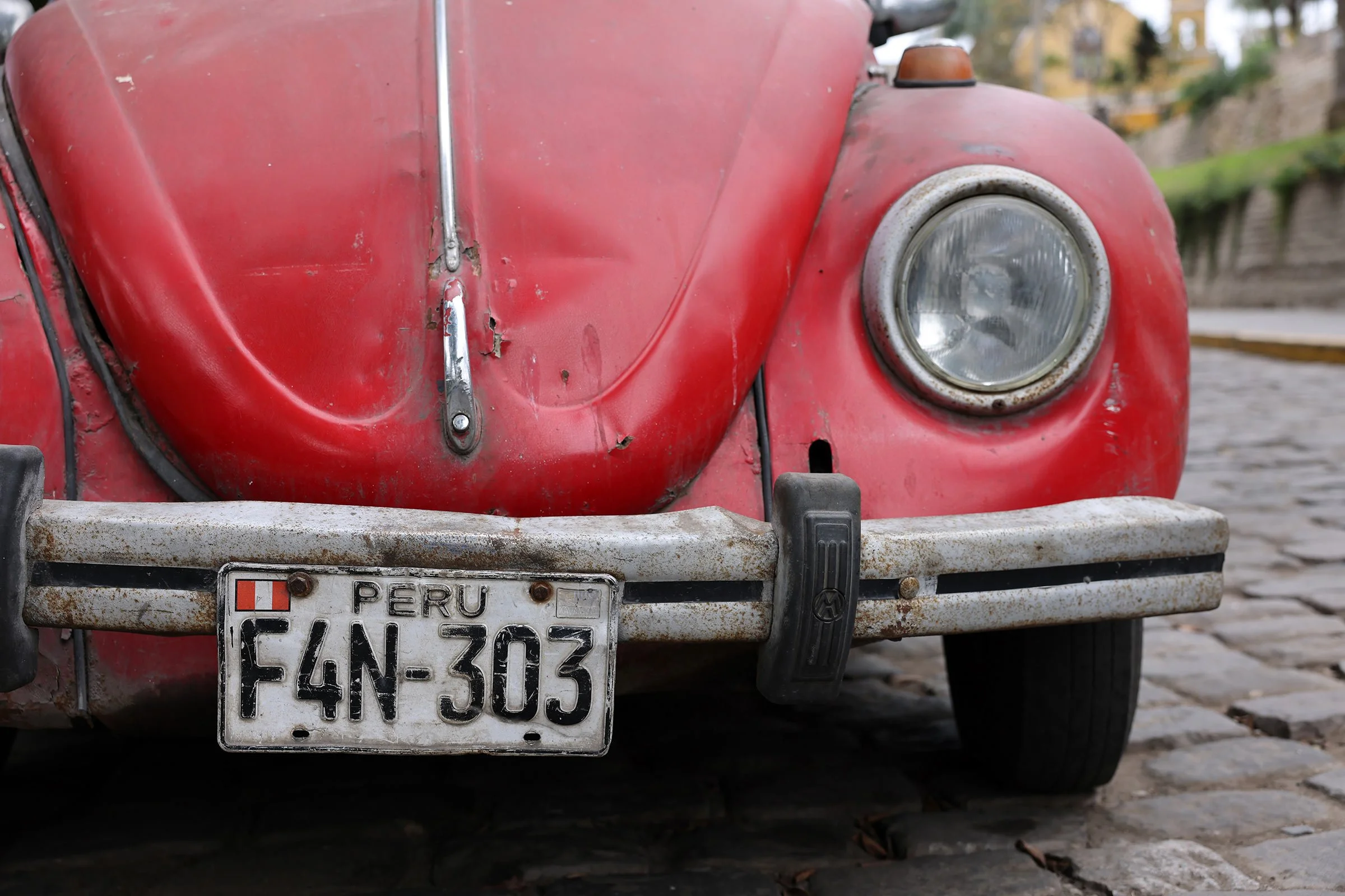 En sliten gammal röd Volkswagen Beetle i Lima med peruansk registreringsskylt