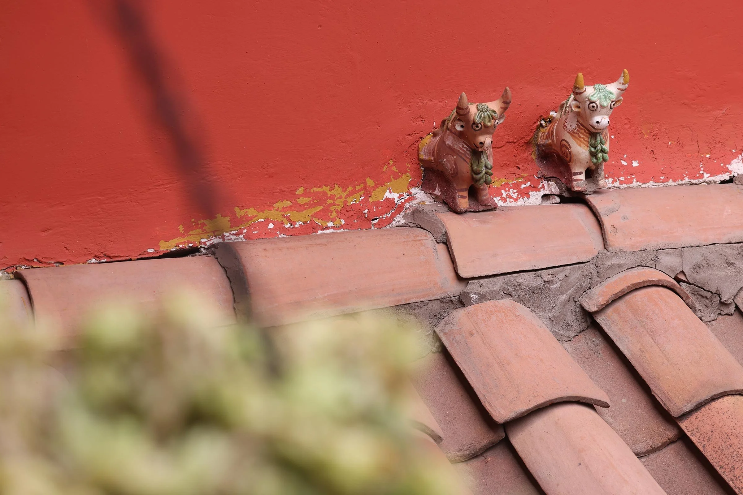 Små tjurar i lera, Torito de Pucará, på taket av ett hus i Cusco, Peru