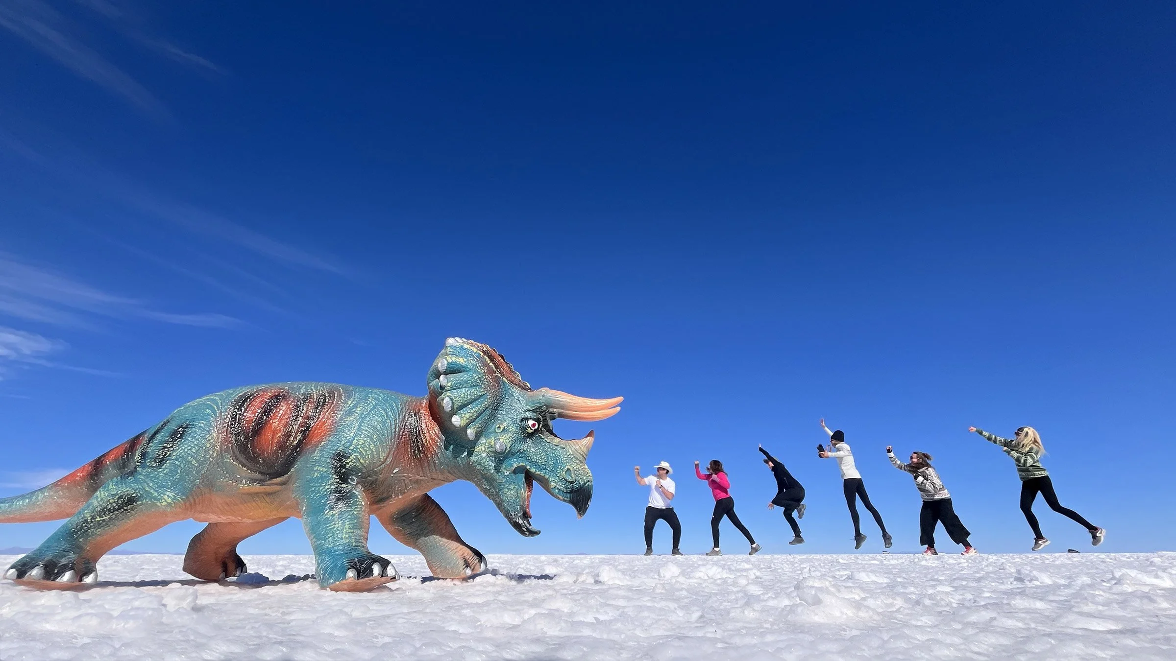 Små människor som slåss mot en triceratops i Salar de Uyuni, Bolivia