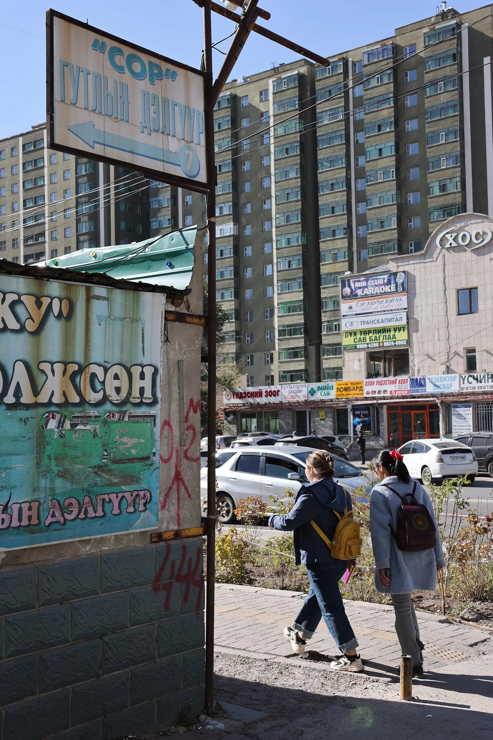 Två kvinnor på en trottoar framför ett stort lägenhetskomplex i Ulaanbaatar, Mongoliet