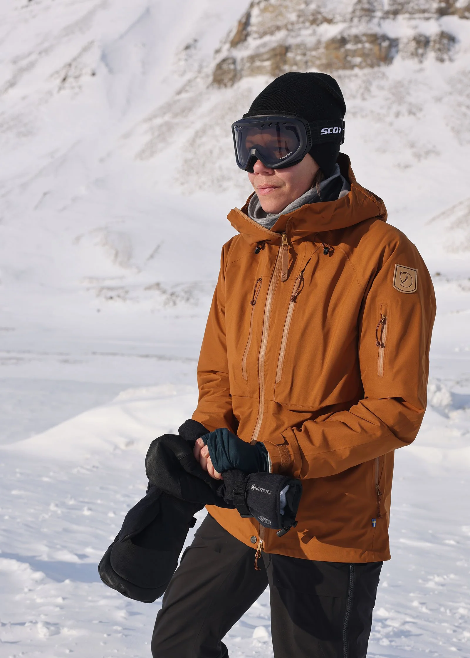 Med tjocka vantar, skalkläder och skidglasögon en solig dag på ett vintrigt Svalbard