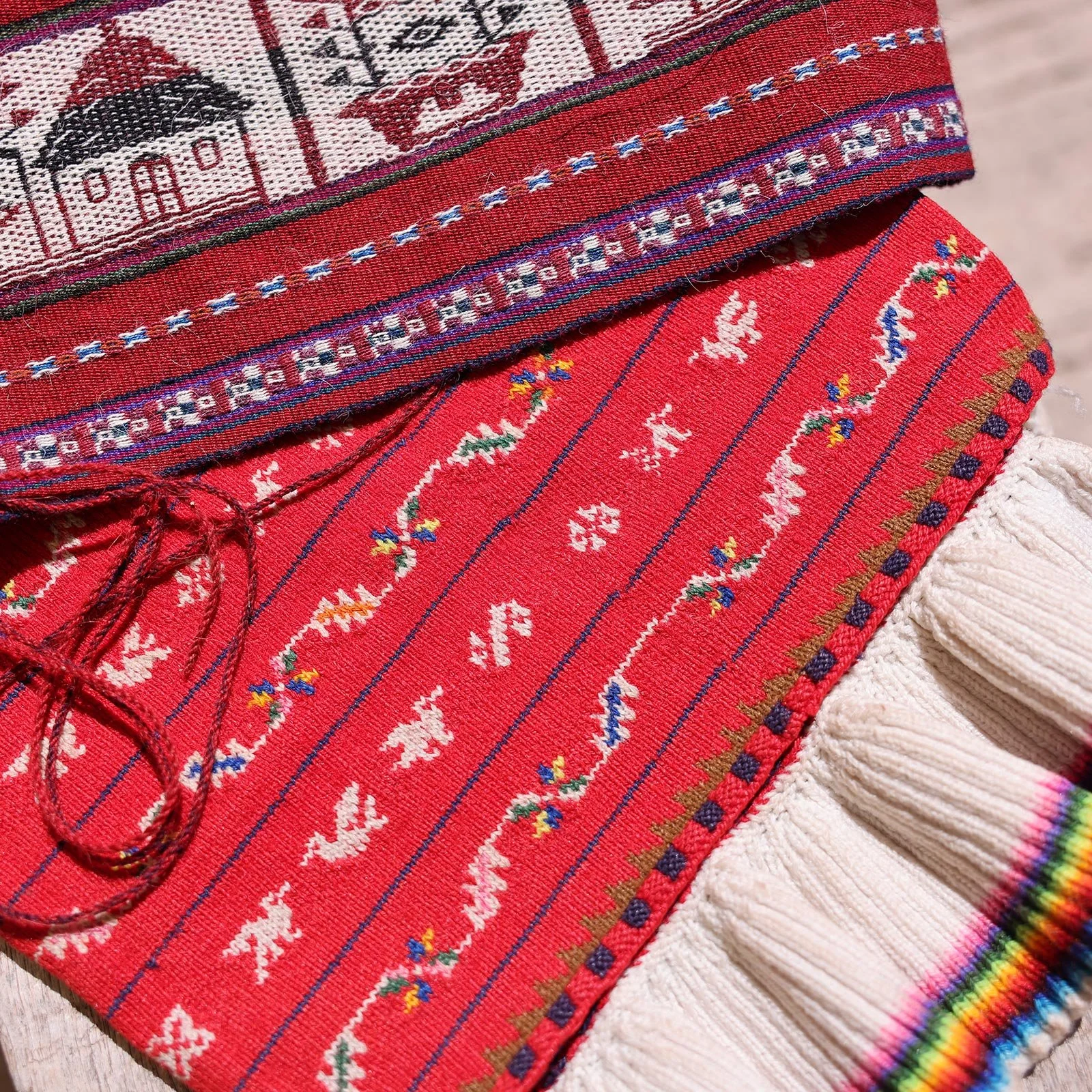 Textilhantverk med hus och fåglar i röda toner på ön Taquile i Titicacasjön, Peru