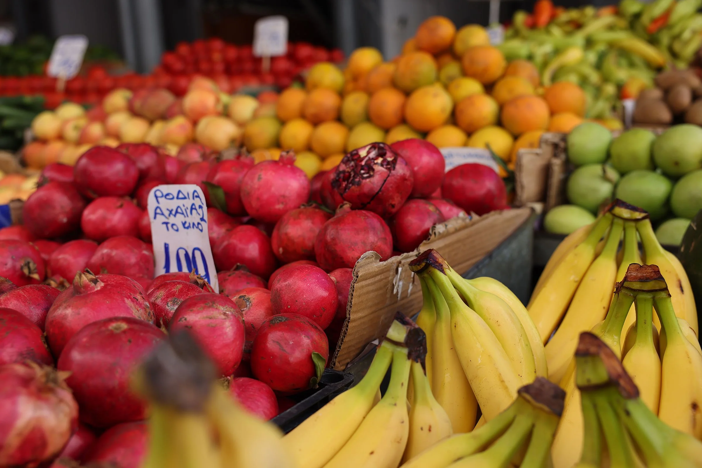 Granatäpplen, bananer och apelsiner på en matmarknad i Aten, Grekland