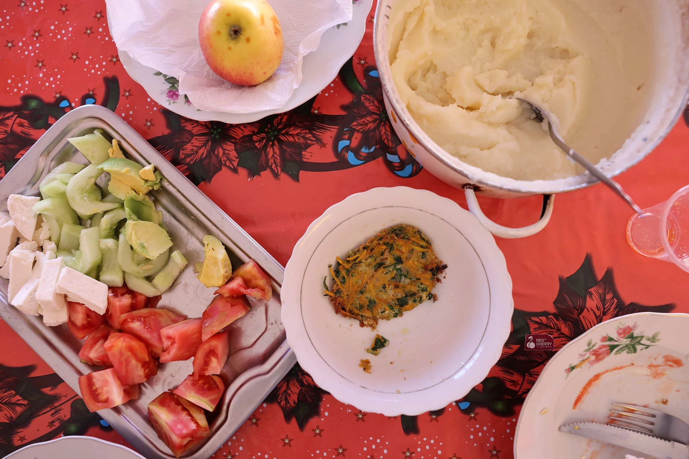 Grönsaker, vegetarisk biff, potatismos och ett äpple uppdukat på vitt porslin på en röd julduk i Bolivia
