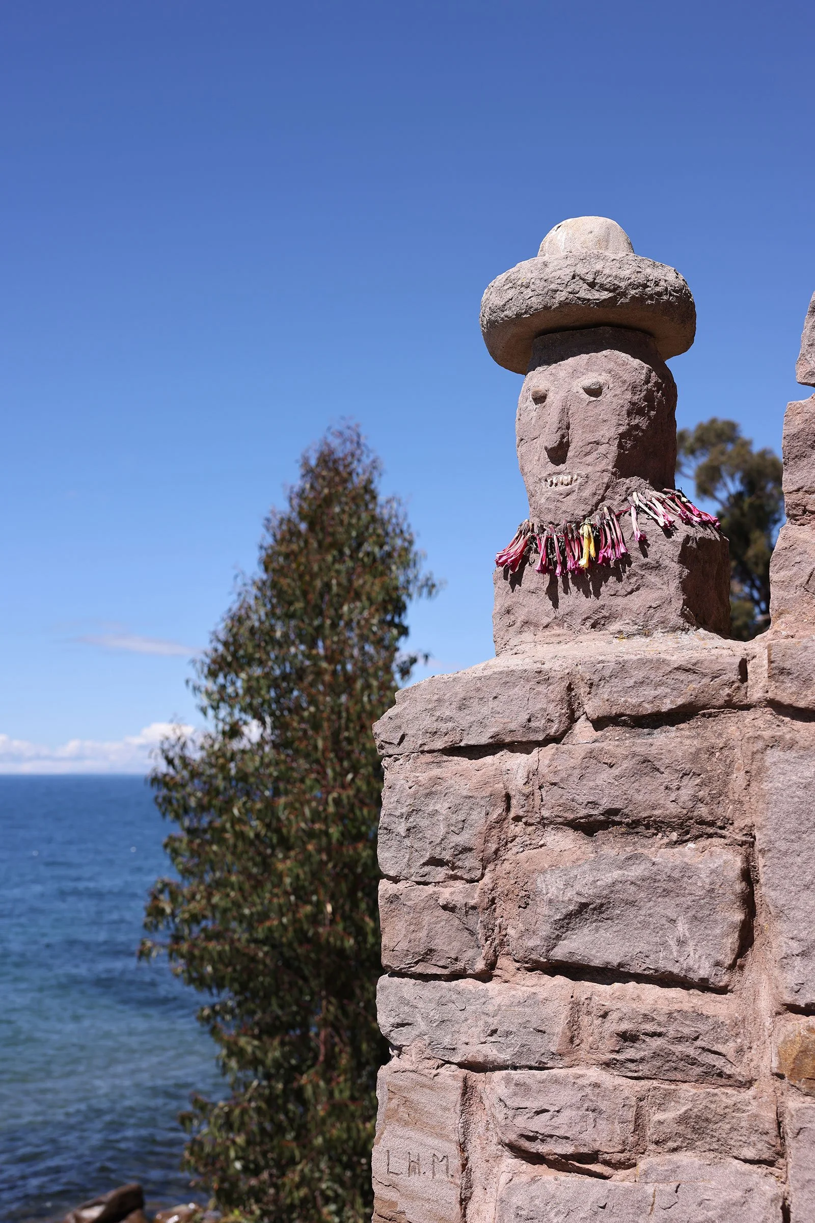 Detalj i form av ett huvud med hatt på en av stenbågarna som finns på ön Taquile i Titicacasjön, Peru