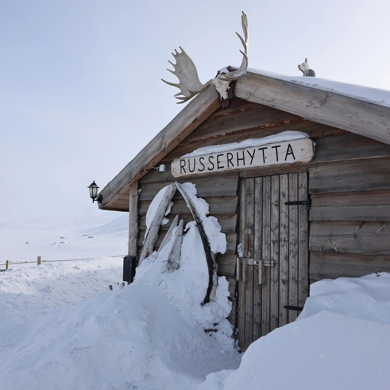 En trähytta med namnet "Russerhytta" i ett snölandskap på Svalbard