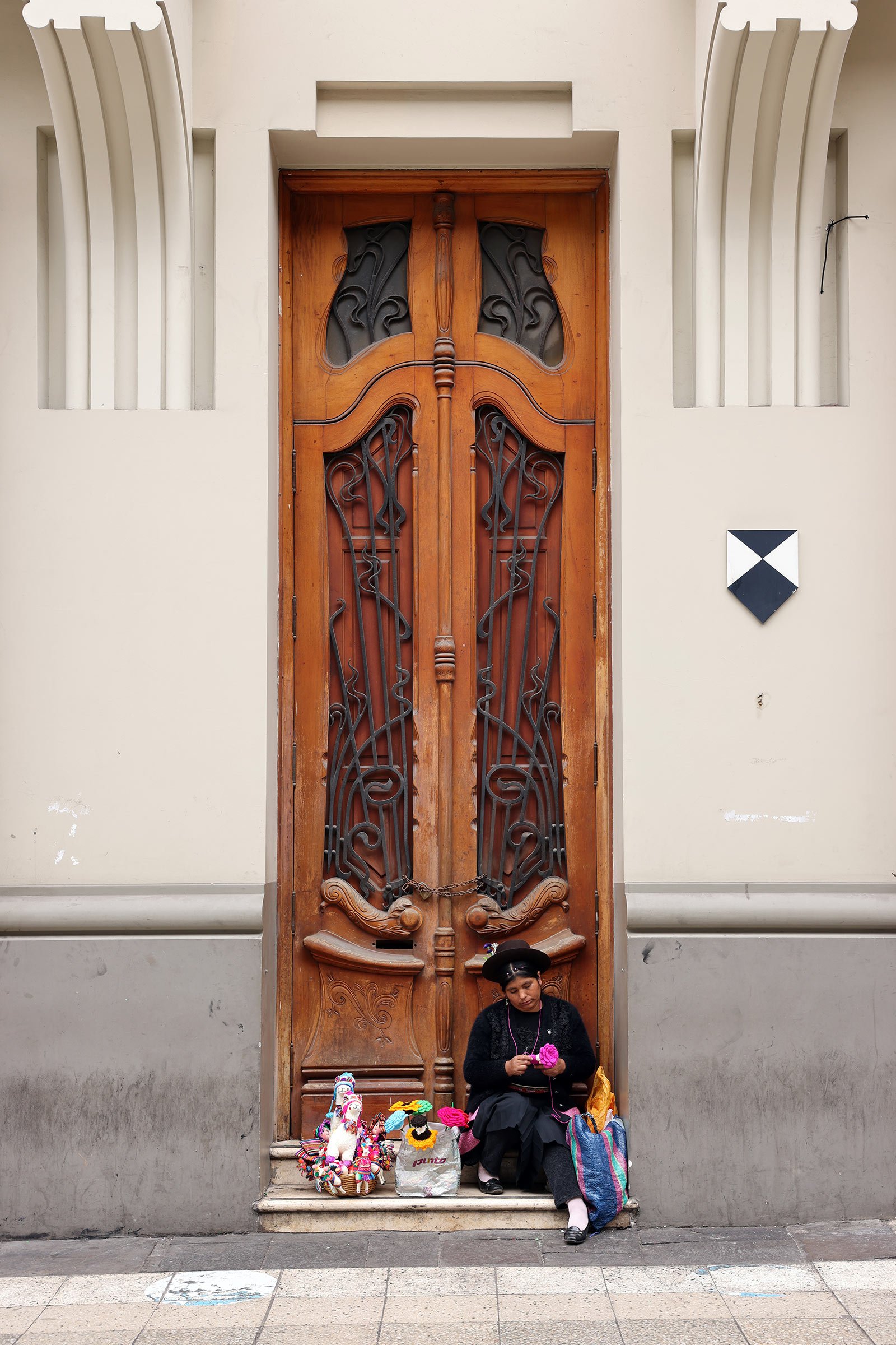 En kvinna som sitter framför en vacker trädörr i art nouveau-stil i Lima, Peru