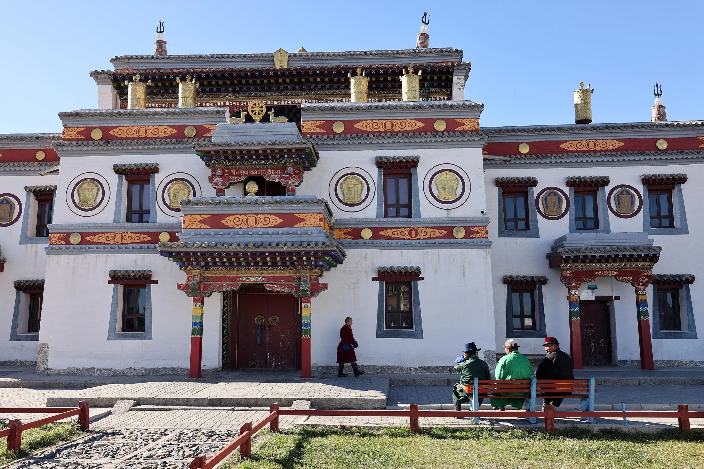 Tre män på en bänk och en munk utanför Erdene Zuu-klostret i Mongoliet