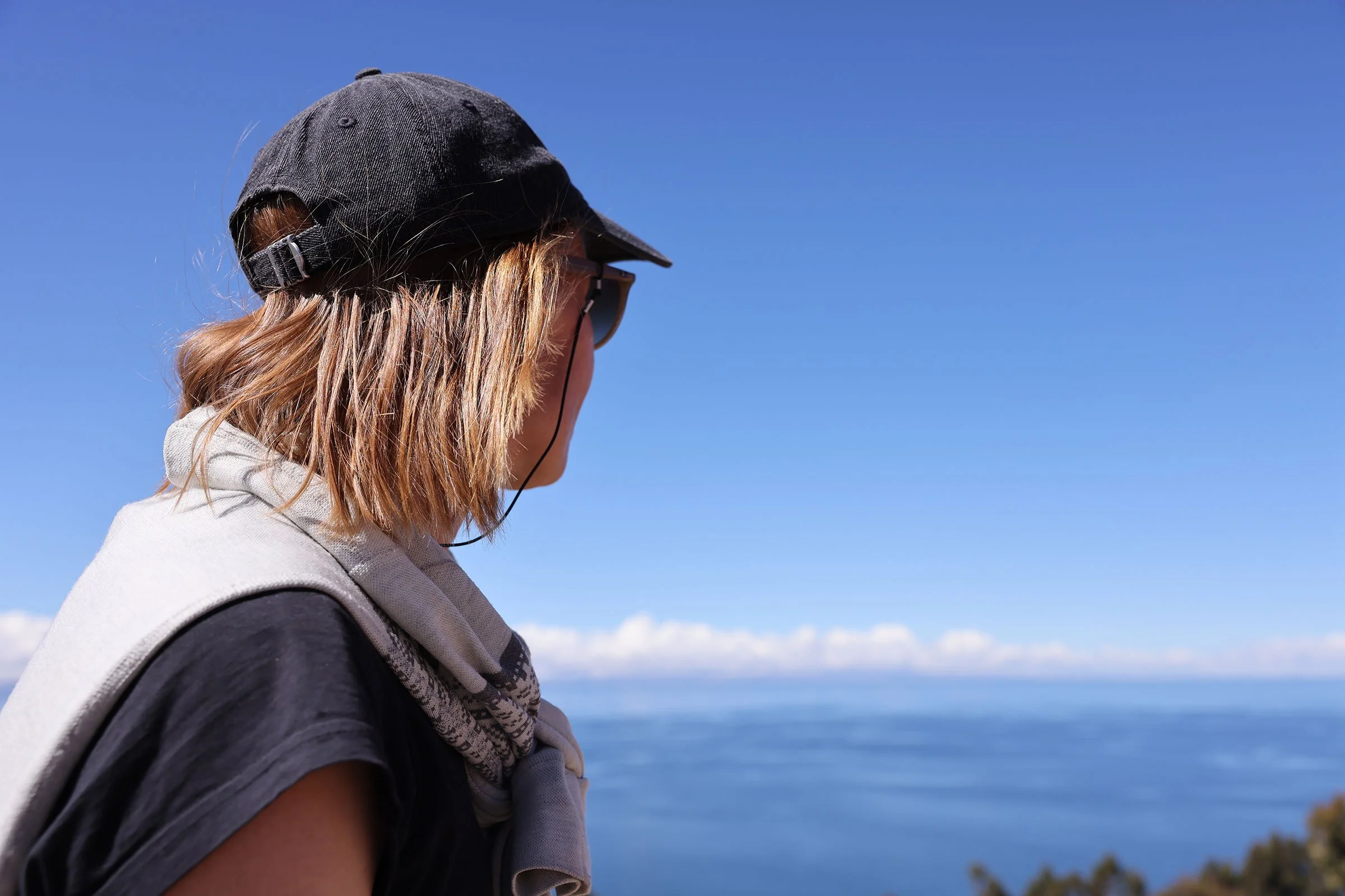 En person i keps och solglasögon som blickar ut över Titicacasjön, Peru